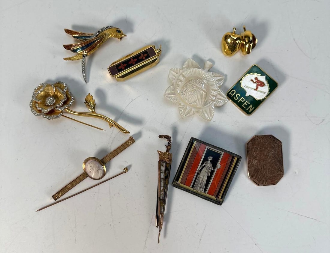 DISCOVERY LOT: VINTAGE BROOCHES: A collection of ten diverse vintage brooches, pins, and small decorative objects, varying in material, shape, and subject matter, against a white background. Provenance: From a New York Collector D