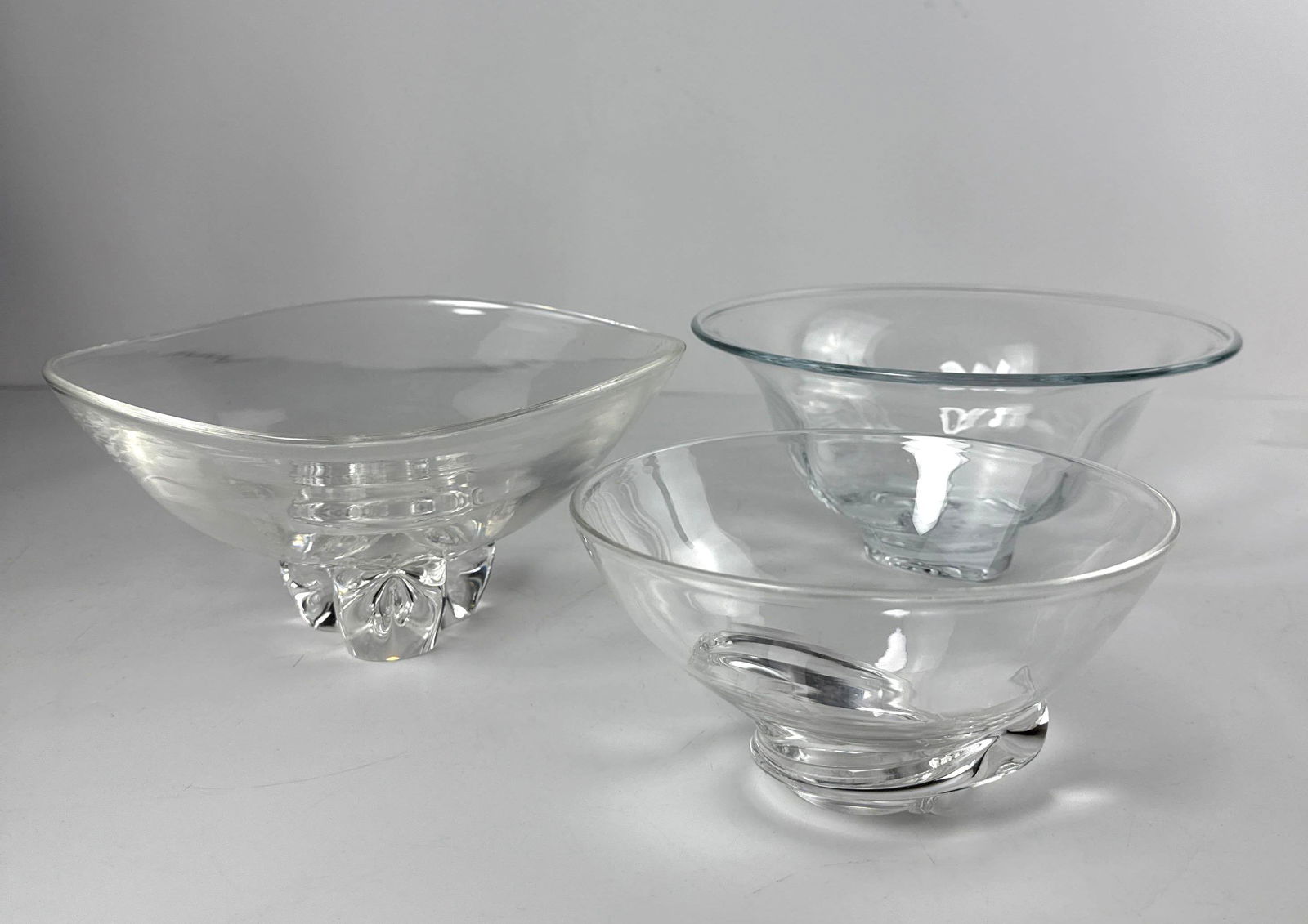 TRIO OF AMERICAN STUDIO GLASS BOWLS, TWO STEUBEN , ONE SIMON PEARCE: A trio of American studio glass bowls, with two from Steuben and one from Simon Pearce. Dimensions: 2 larger : 10.5” x 4.75” Artist or Maker: Steuben & Simon Pearce Provenance: From
