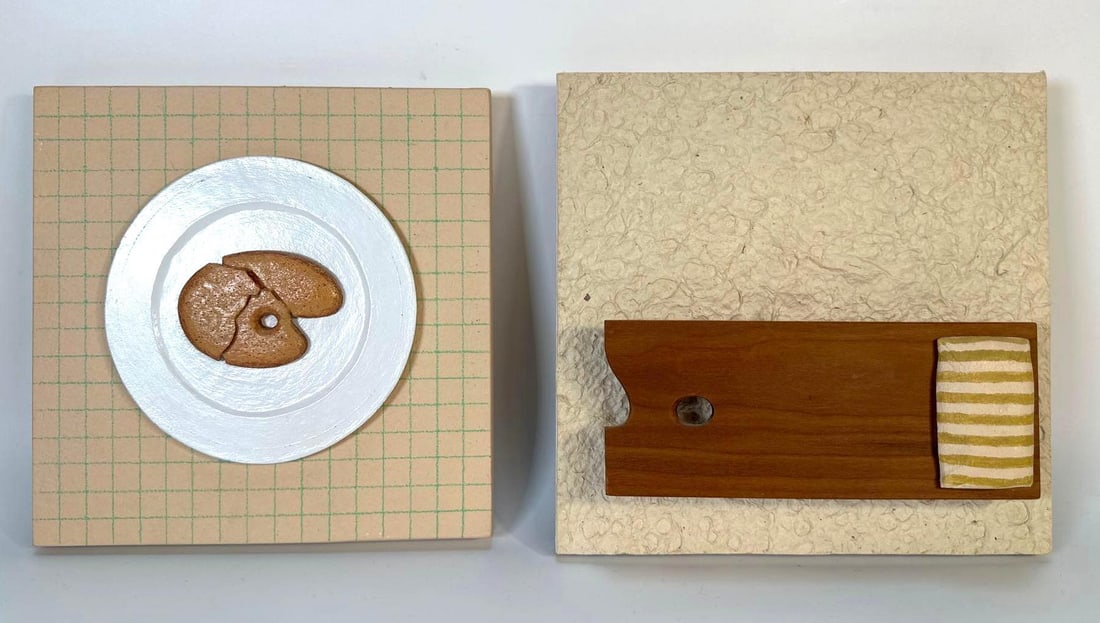 PAIR OF JOSEPH CAROFF DIMENSIONAL ART PIECES: Two pieces of mixed-media dimensional art by the designer of the 007 logo. The left piece, titled "The Last Cookie on Earth", depicts a round, white plate with a brown cookie shaped like an ar