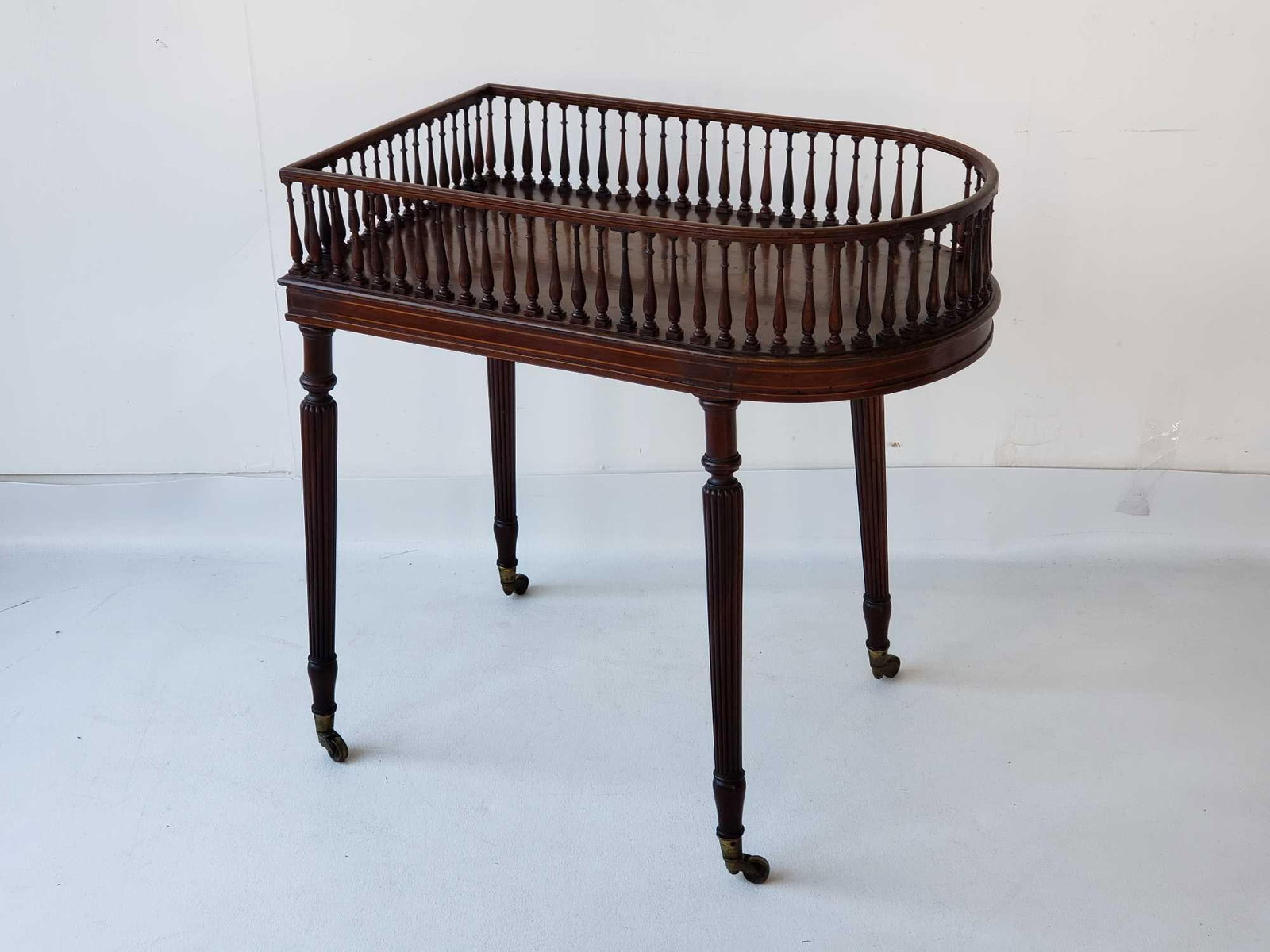 REGENCY INLAID MAHOGANY SPINDLE SIDED ANTIQUE BOTTLE STAND: Antique English Regency Mahogany Oval Gallery Table on Brass Casters. Exceptional piece, presents beautifully, but please NOTE: missing two small balusters. Decanters are NOT included, and only shown 