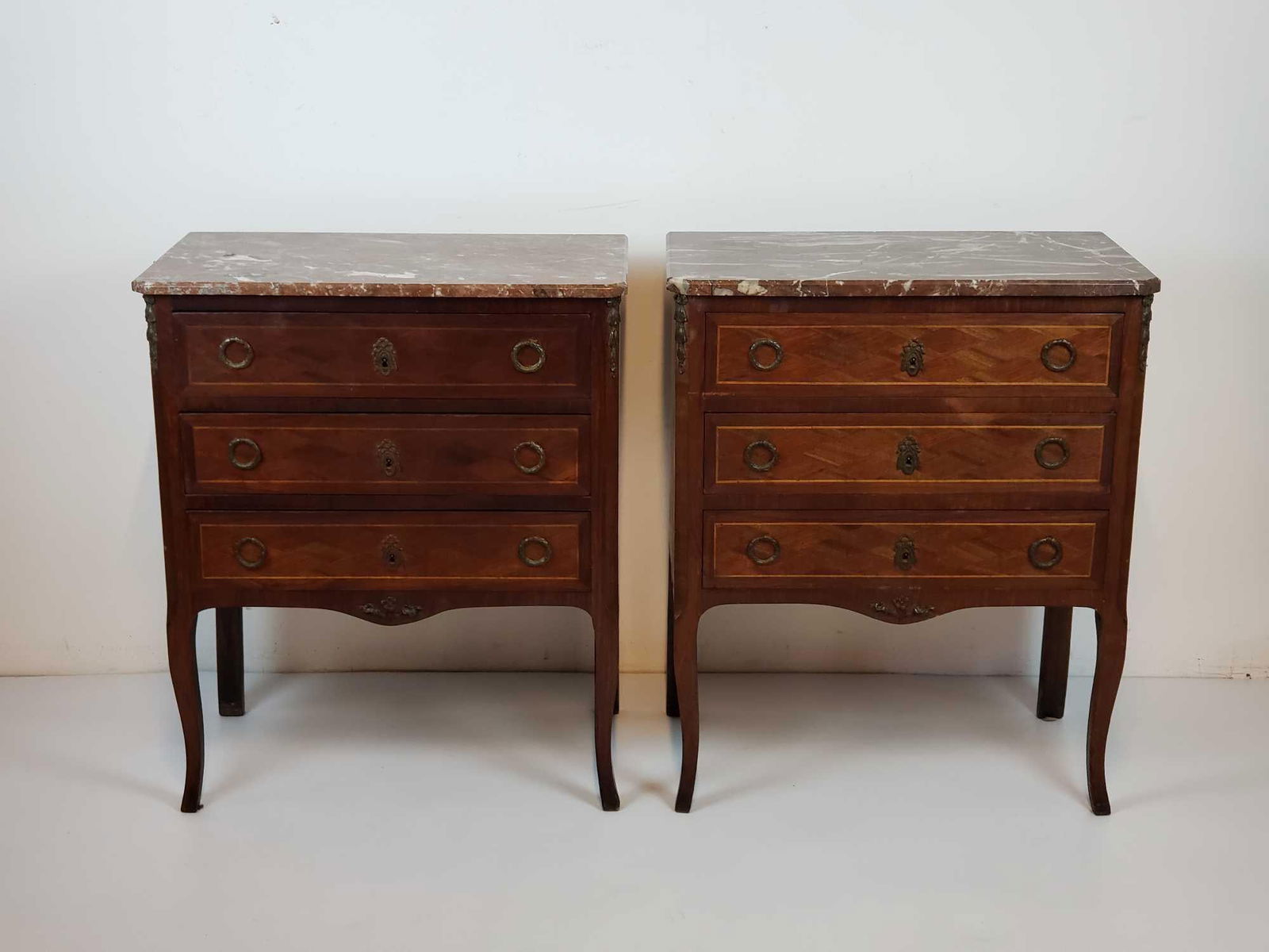 PAIR OF LOUIS XV STYLE INLAID MARBLE TOP COMMODES: A pair of matching Louis XV style commodes, each featuring an inlaid design, a fitted marble top, and decorative brass mounts. Dimensions: 32"T x 26.5"W x 15"D Artist or Maker: Unknown Provenance: