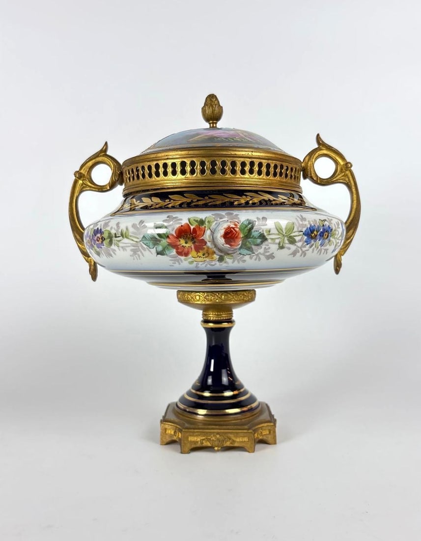 SEVRES CHATEAU DES TUILERIES PORCELAIN & BRONZE CASSOLETTE | POTPOURI VASE: A stunning, lidded porcelain poutpoutri vase, mounted on a gilded bronze base, featuring a vented central body hand painted with colorful florals and a cobalt blue rim. The bronze mounts include elabo