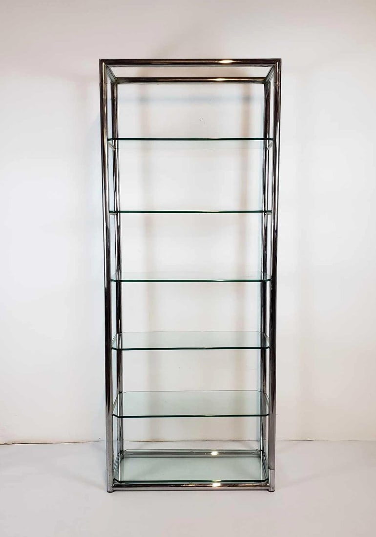 MID CENTURY MODERN CHROME AND GLASS ETAGERE IN THE MANNER OF MILO BAUGHMAN: A tall, rectangular etagere featuring six fixed glass shelves supported by a polished chrome frame constructed from square tubular metal. Dimensions: 78"H x 31.75"W x 14"D Maker: Unknown