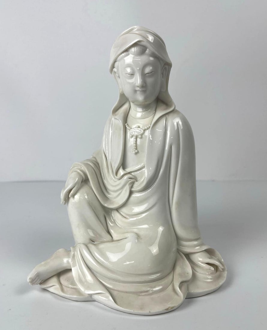 BLANC DE CHINE HOODED WOMEN SEATED GUANYIN: *A Chinese porcelain sculpture of a seated woman, guanyin. Dimensions: 8.5" x 6.25" Artist/Maker: unknown Provenance: From the estate of a nonagenarian lifelong collector of Asian art. Notes: Altho