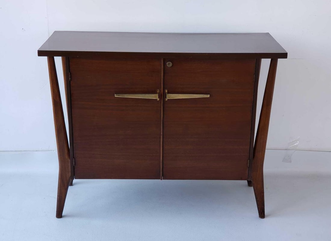 MID CENTURY MODERN WALNUT VENEER LIQUOR CABINET WITH SCULPTED FLOATING LEGS AND LAMINATE TOP: *A modern liquor cabinet Dimensions: 29.75"h x 38"w x 15.5"d Maker: Unknown Provenance: A New York Collector Notes: Although care is taken to photograph and describe the item, absence of a conditio