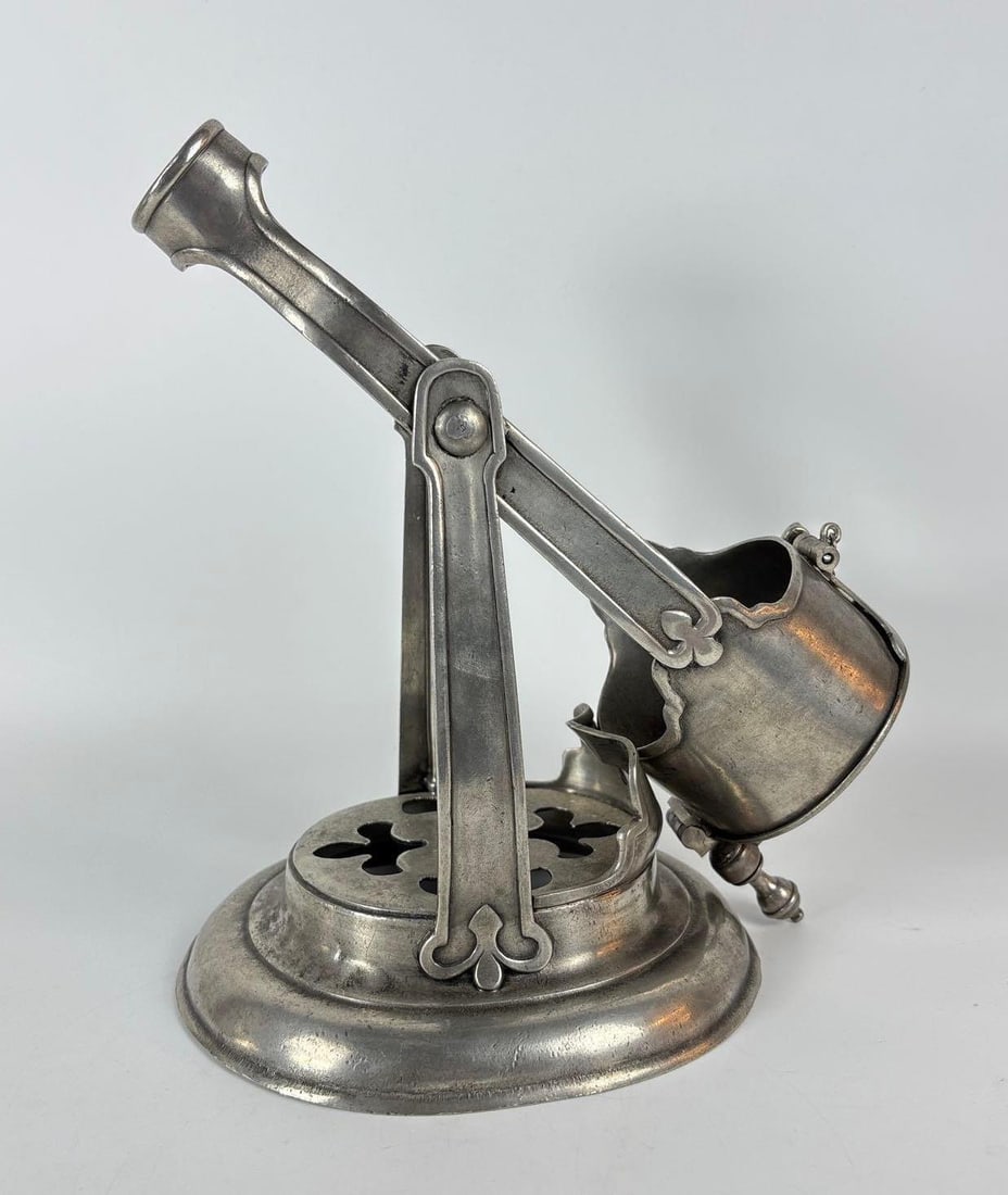 LA MAISON DE L'ETAIN RARE ANTIQUE FRENCH PEWTER TILTING WINE OR CHAMPAGNE BOTTLE CRADLE HOLDER: An antique French pewter wine or Champagne bottle holder/cradle. The piece has a tilting mechanism supported by a base with open, pierced quatrefoil designs. Stamped La Maison De L'ETAIN Dimensio