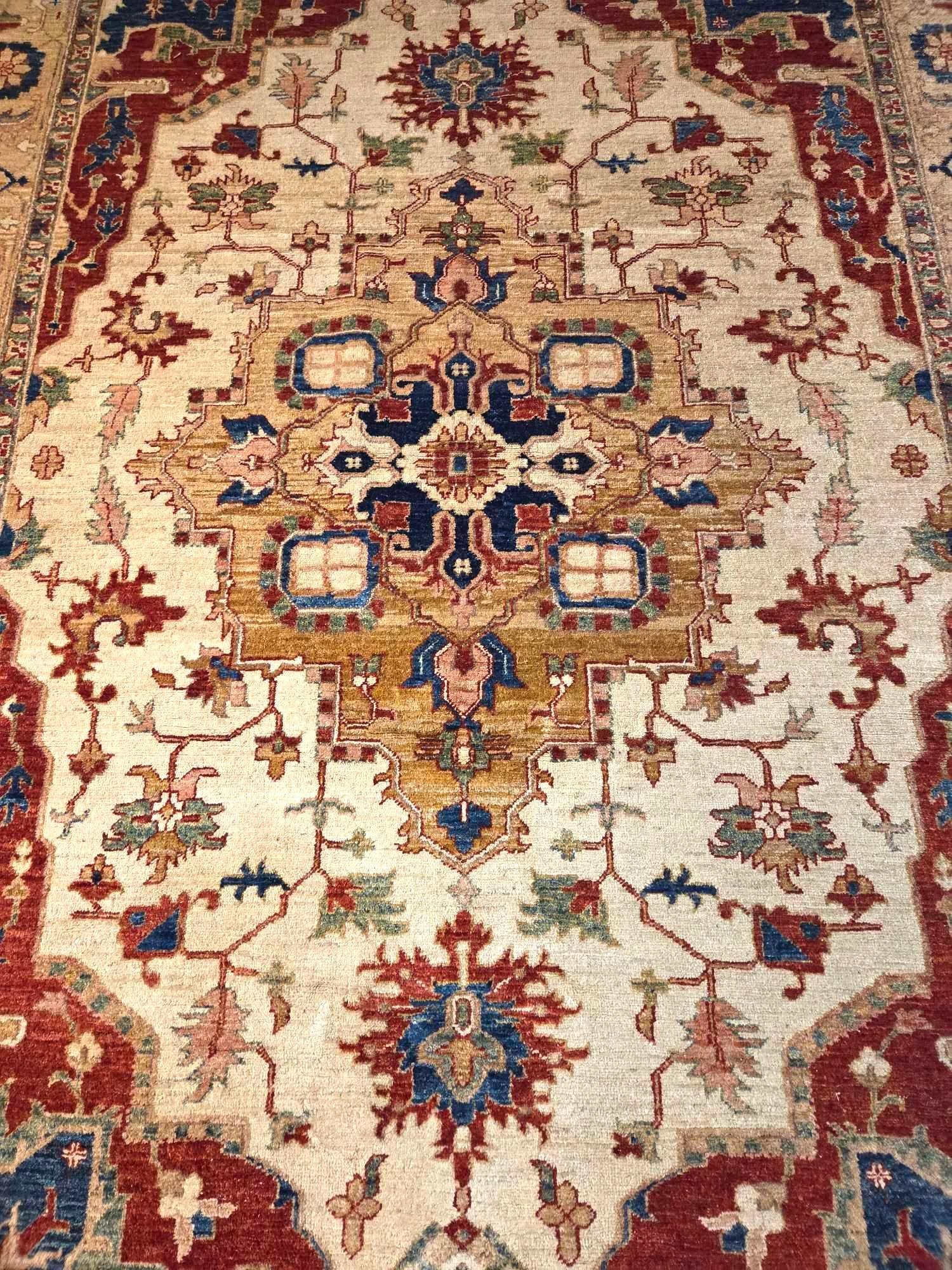 ORIENTAL RUG BEIGE GROUND: A rectangular, hand-knotted rug featuring a central medallion executed in a traditional geometric and floral pattern in beige/ivory for the ground, and deep red, navy blue, and gold accents for the mo