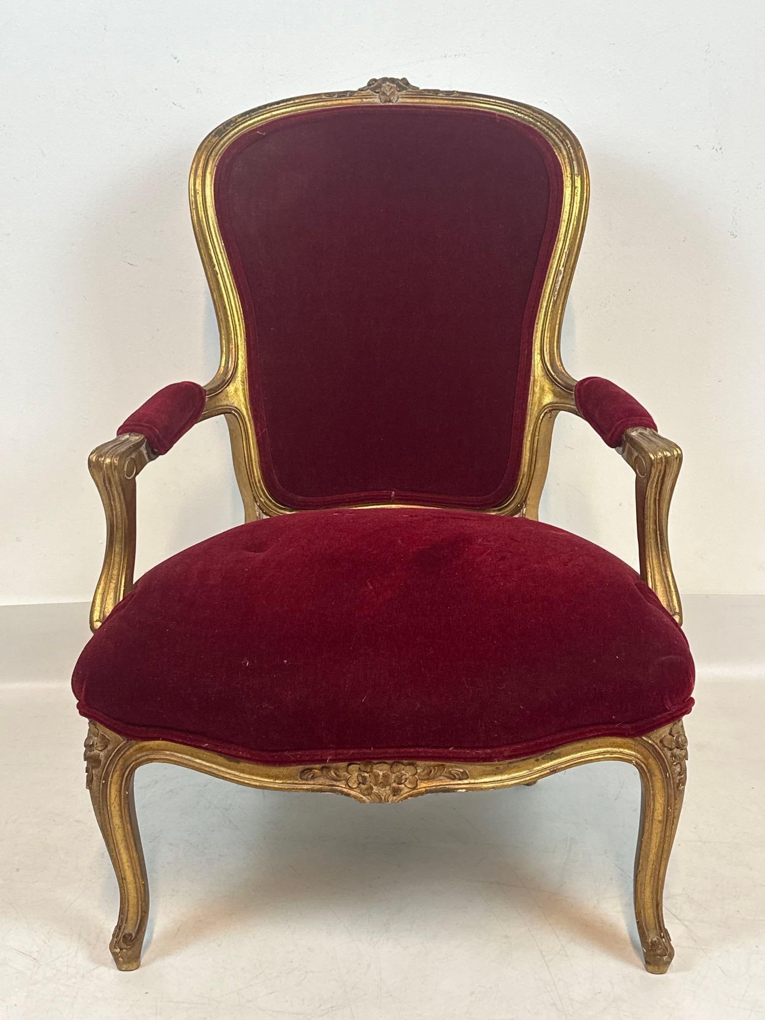 VINTAGE FRENCH LOUIS XV STYLE BURGUNDY VELVET ARMCHAIR: Ornate hand-carved giltwood bergère armchair upholstered in deep burgundy velvet with padded armrests and elegant cabriole legs. Approximate Dimensions: 35”H x 24”W x 25”D Artist