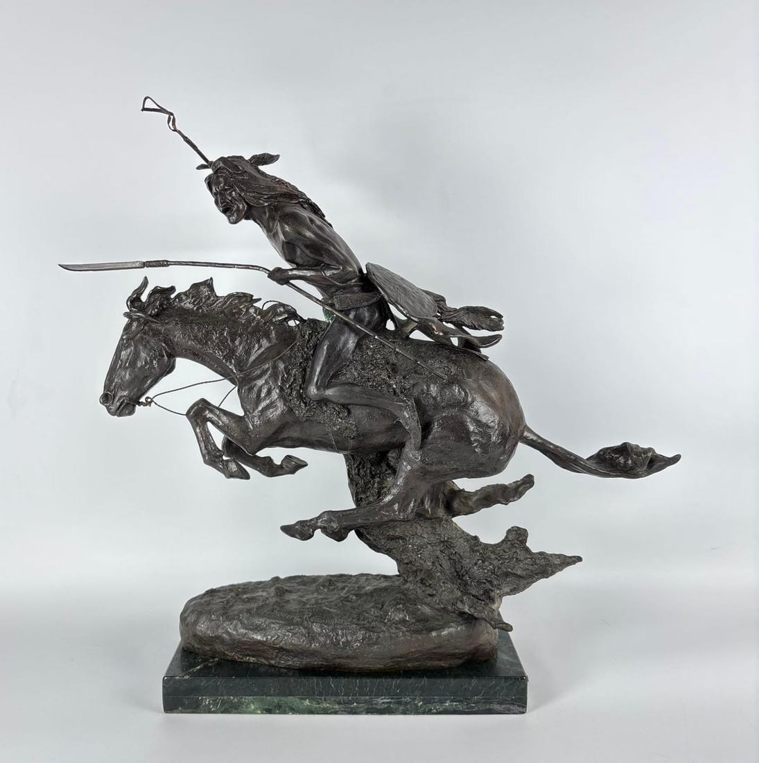 FREDERIC REMINGTON "THE CHEYENNE" LARGE BRONZE SCULPTURE 24": Patinated bronze depiction of a Native American warrior at full gallop with spear and shield supported by a trailing buffalo robe. Approximate Dimensions: 24"H x 23" x 12" Artist or Maker: Unknown
