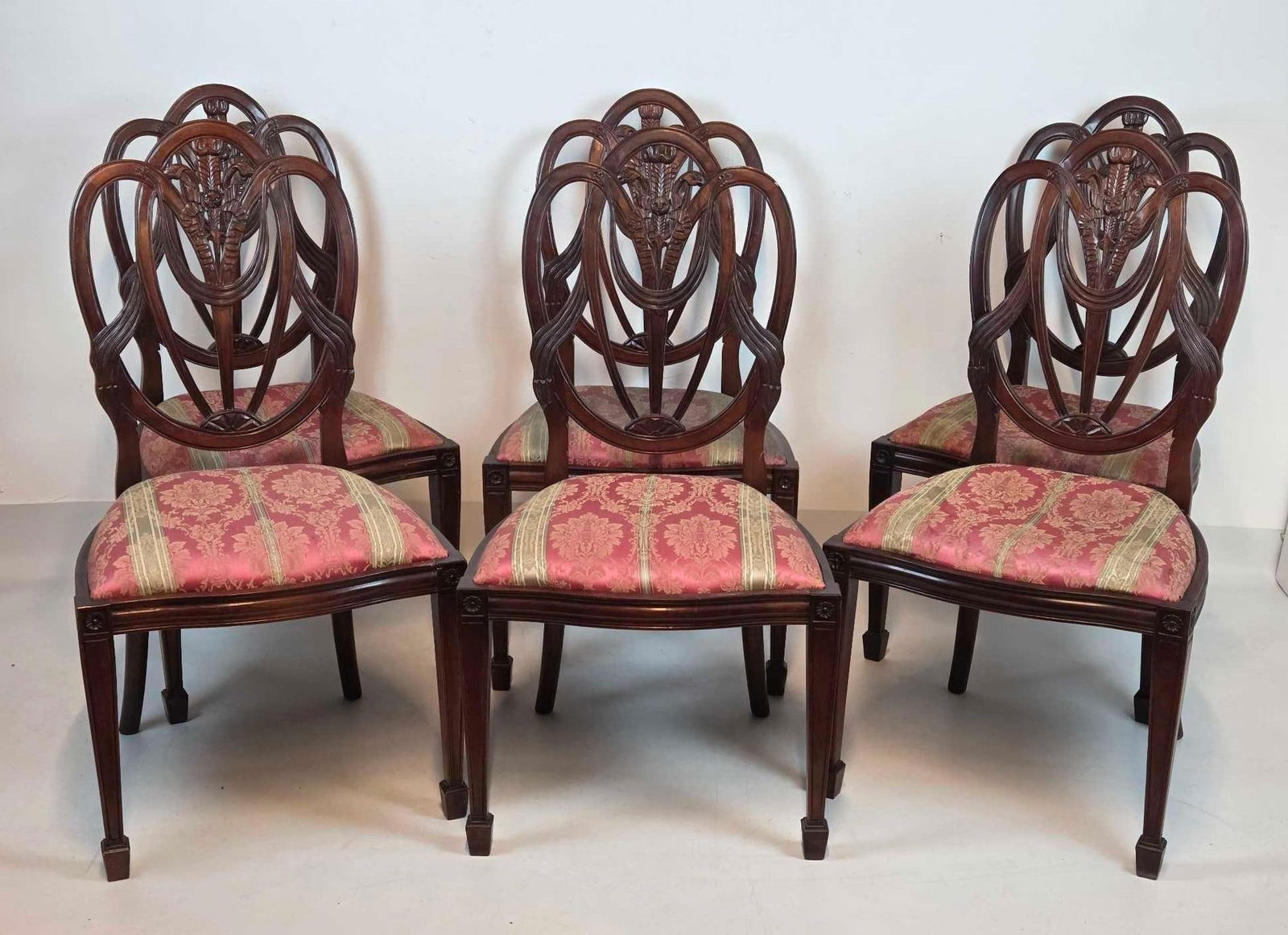 SET OF SIX HEPPLEWHITE STYLE CARVED MAHOGANY DINING CHAIRS: Set of six mahogany dining chairs in the Hepplewhite taste with openwork shield backs, central wheat sheaf and husk carvings, and upholstered seats in pink floral damask fabric. Approximate Dimension