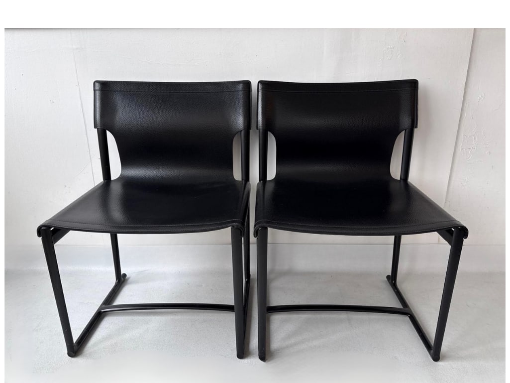 PAIR OF B&B ITALIA MIRTO INDOOR CHAIRS BY ANTONIO CITTERIO: These minimalist dining chairs consist of black thick saddle leather seats and backs stretched over a matching black die-cast aluminum frame. Approximate Dimensions: 23” x 20” x 32”