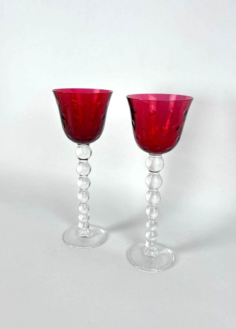 PAIR OF RED ST LOUIS FRENCH CRYSTAL BUBBLES WINE GLASSES: A pair of red French crystal wine glasses featuring the iconic Bubbles pattern by Saint-Louis, distinguished by a stack of graduated crystal marbles on the stem. Approximate Dimensions: 10"T Maker: