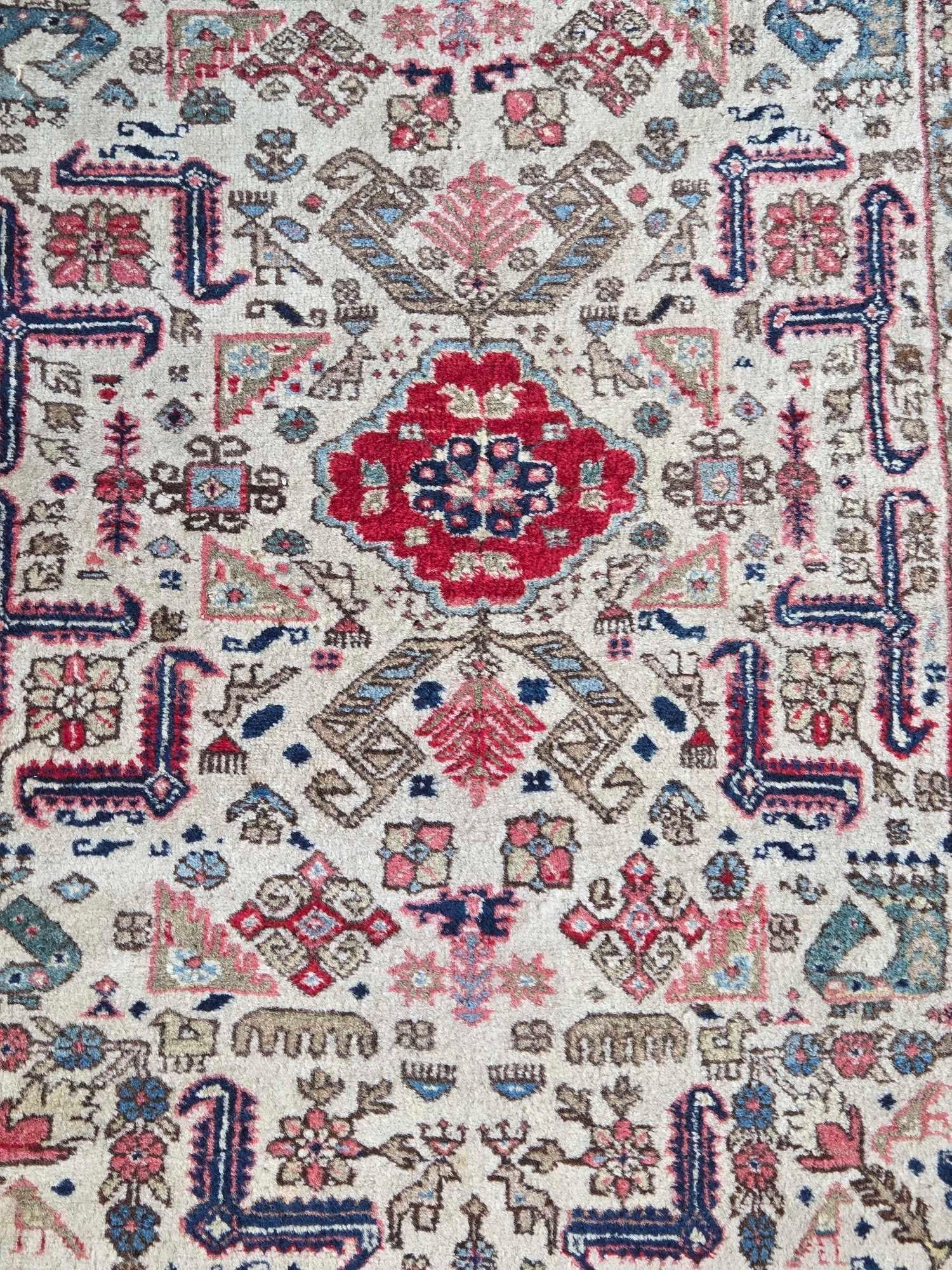 VINTAGE BIRD AND ANIMAL MOTIF TRIBAL OUSHAK WOOL THROW RUG: *A hand-knotted wool pile throw rug featuring a repetitive tribal geometric pattern in an earth-toned color palette with stylized bird and animal figures scattered throughout the central field and bor