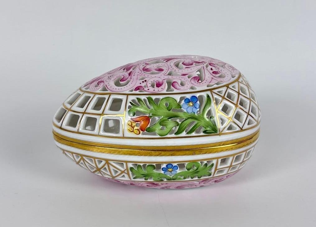 VINTAGE HEREND HUNGARY HAND-PAINTED RETICULATED EGG BOX: Hand-painted Hungarian porcelain egg-shaped trinket box with a pierced reticulated lid, 24K gold gilt accents, and floral motifs. Approximate Dimensions: 2.5" x 3" x 4.5" Artist or Maker: Unknown Pro