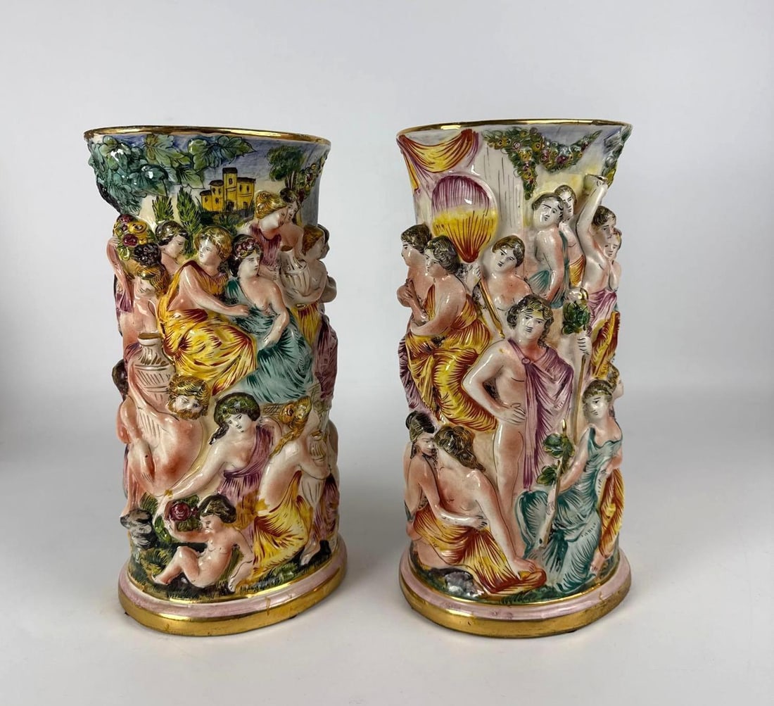 PAIR VINTAGE CAPODIMONTE HAND PAINTED RAISED RELIEF BACCHANALIAN VASES URNS: *This matching set of two vases is made of hand-painted Italian porcelain and decorated with continuous, high-relief scenes of numerous figures in Bacchanalian revelry. Approximate Dimensions: 5&rdquo