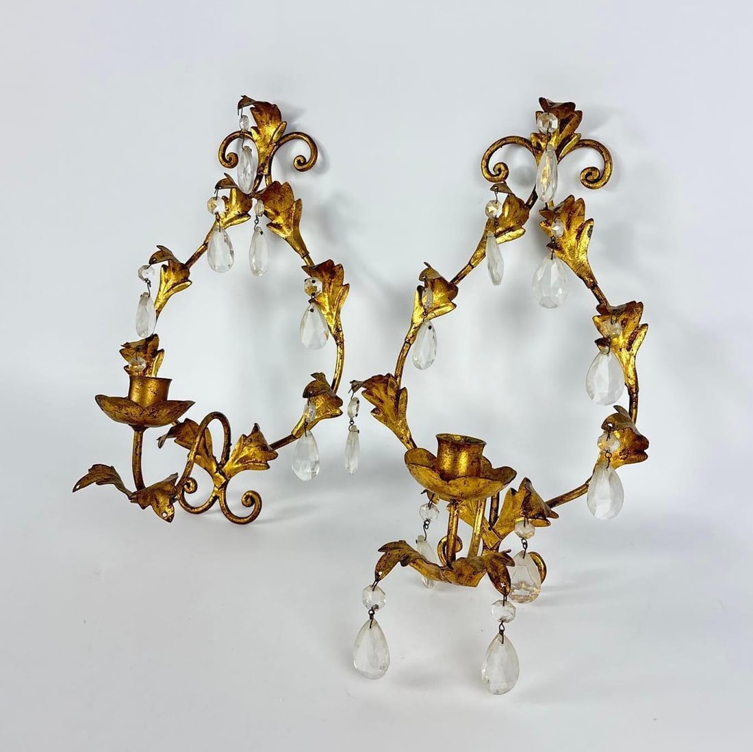 PAIR OF ITALIAN GILT METAL AND CRYSTAL PRISM CANDLE WALL SCONCES: Set of two gold finished metal leaf and vine motif wall mounted candle holders with hanging teardrop glass crystal prisms. Approximate Dimensions: 13"H x 8"W x 6"D Artist or Maker: Unknown
