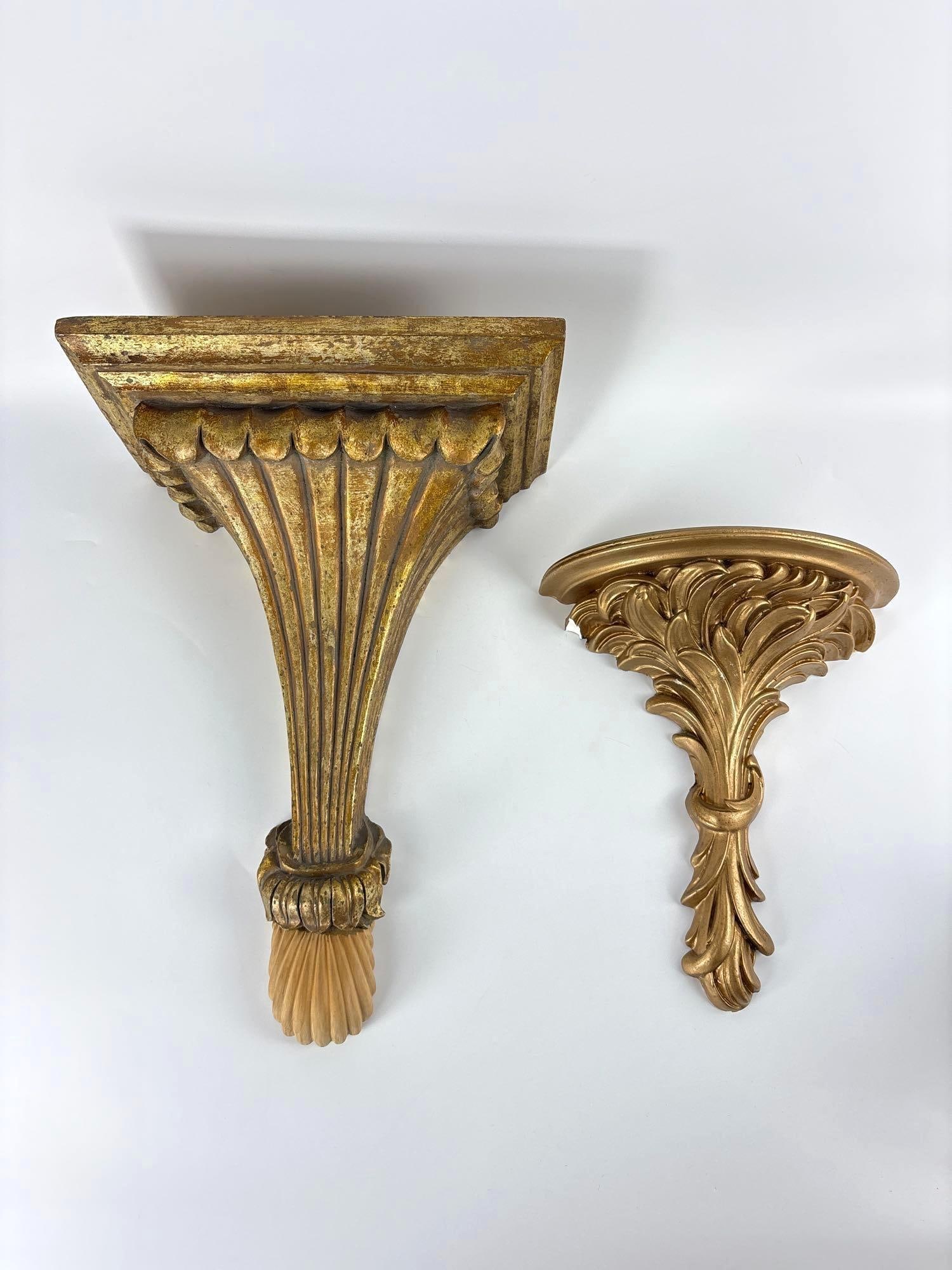 PAIR OF GILT WALL SCONCE SHELVES: Two gold toned wall sconces of different sizes and designs, featuring ornate classical motifs such as fluted columns, acanthus leaves, and scalloped edges. (Note repair to larger) Larger Approximate