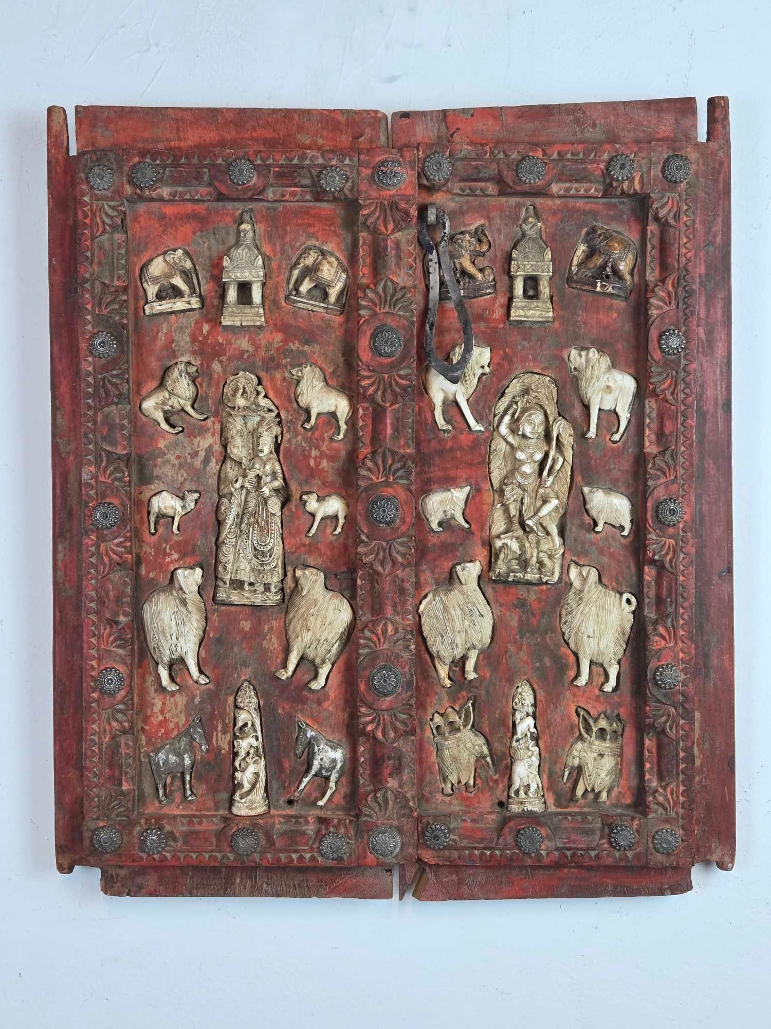 ANTIQUE INDIAN CARVED WOOD DOOR PANEL WITH BONE INLAYS AND IRON STUDS: Intricately hand-carved solid wood architectural door panel with decorative iron studs and inset bone carvings of Hindu deities and animals Approximate Dimensions: 21” x 18” Artist or Ma