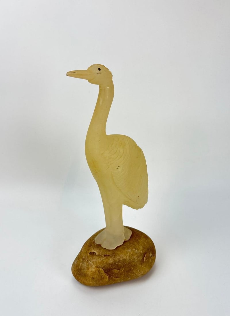 HAND-CARVED FROSTED GLASS CRANE FIGURINE ON NATURAL STONE BASE: Frosted yellow glass heron bird sculpture mounted on a natural river rock stone base. Approximate Dimensions: 12.5" h x 5.5" Artist or Maker: Unknown Provenance: From a New York Collector Not