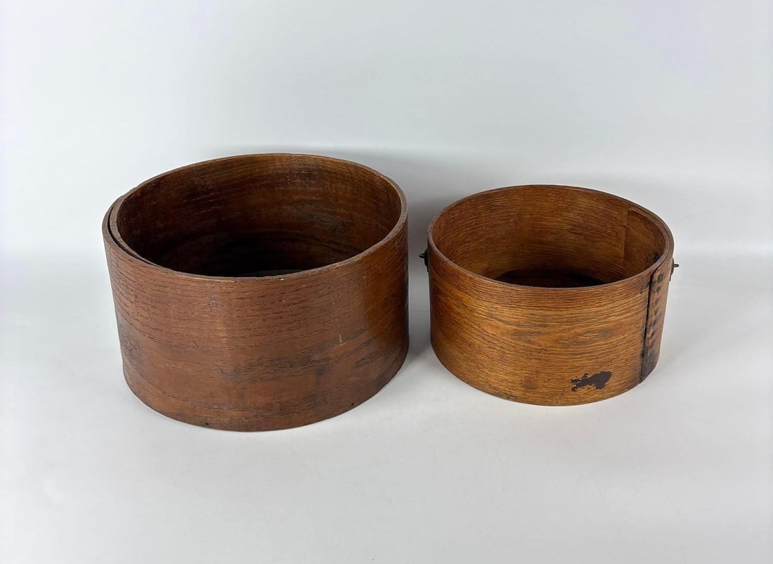 PAIR OF ANTIQUE MAINE BENTWOOD GRAIN MEASURES BY WHITTEN & WIGGIN ATTR.: Set of two 19th-century bentwood buckets with iron tack seams and a wire bail handle with a turned wood grip. Approximate Dimensions of Largest: 6.5"H x 11" Dia Maker: Unknown Provenance: