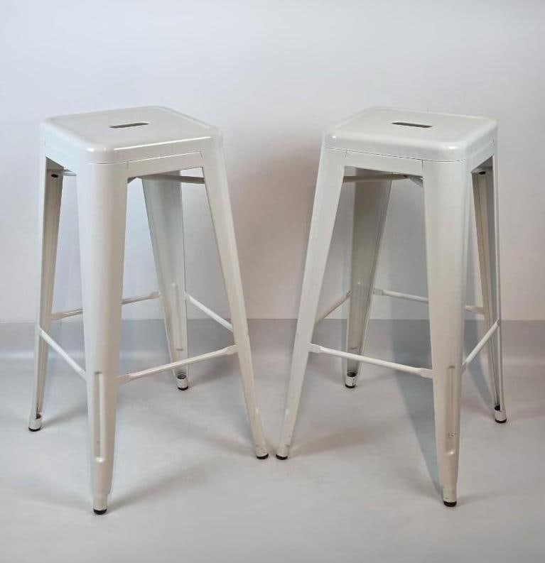 PAIR OF BLUE OCEAN TRADERS WHITE METAL BOUCHON BAR STOOLS: *Set of two stackable white powder-coated industrial metal bar stools with integrated seat handles and tapered legs. Approximate Dimensions: 30"h x 17"w x 17"d Artist or Maker: Blue Ocea
