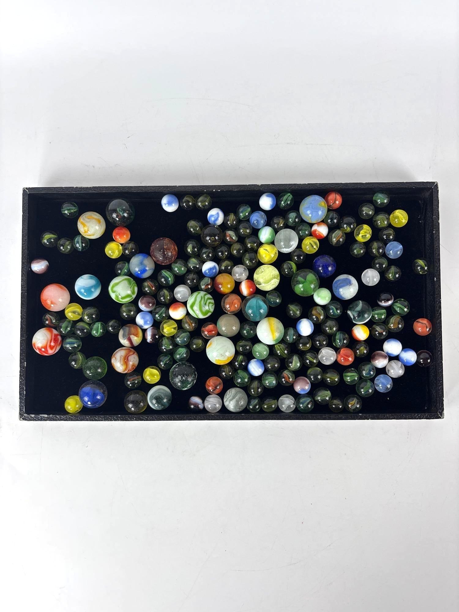 COLLECTION OF VINTAGE MID-CENTURY MACHINE-MADE GLASS MARBLES: Assorted lot of early to mid-20th century translucent and opaque glass spheres in varied colors including cat's eyes, swirls, and patches. 2.57 lbs Approximate Dimensions: Various Artist or Maker