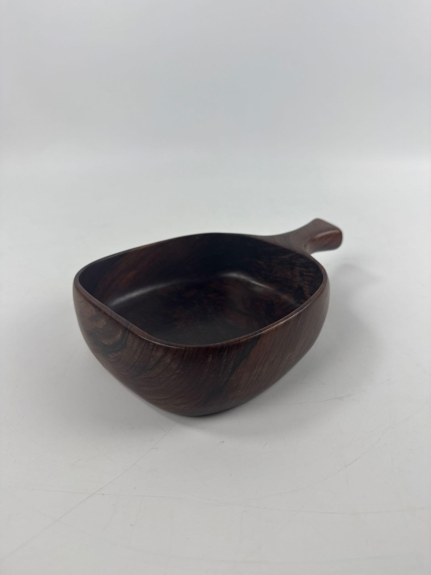 VINTAGE JEAN GILLON BRAZILIAN JACARANDA WOOD ART BOWL MID CENTURY MODERN: Hand-carved solid Brazilian Rosewood sculptural vessel with organic integrated handle produced by Wood Art circa 1960. Approximate Dimensions: 2”h x 9”w x 5.75”d Artist or Maker: Jea