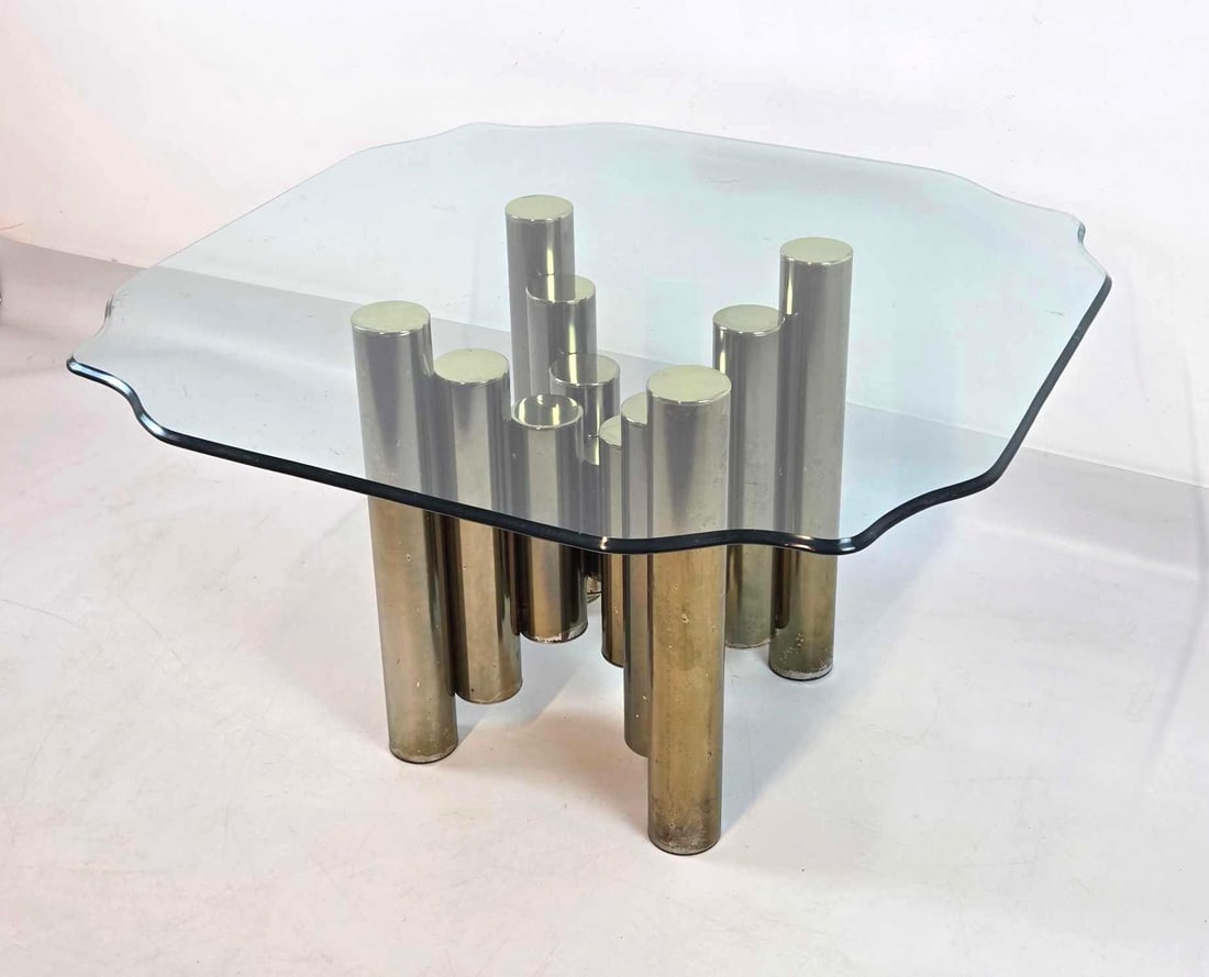 BRASS PIPE CYLINDER BASE GLASS TOP COFFEE TABLE IN THE STYLE OF TIM BATES FOR PIEFF (1 OF 2): Bundled brass cylinder pedestal base with a beveled glass Approximate Dimensions: 20.5"h x 15"w x 16"d Artist or Maker: Pieff England Provenance: From a New York Collector Notes: