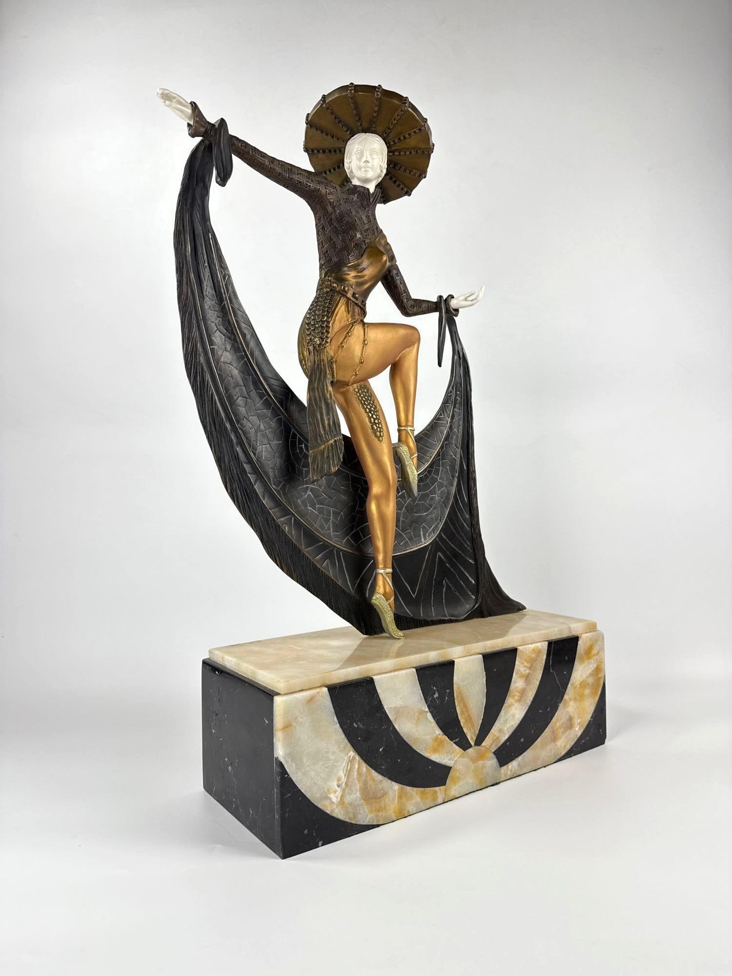 ART DECO STYLE BRONZE SPANISH DANCER FIGURE ON ONYX BASE: Exotic fan dancer in theatrical pose with gold-tone bodice and patterned black cloak on a geometric art deco sunburst plinth. Approximate Dimensions: 27.5”h x 18”w x 6.25”d Artist or