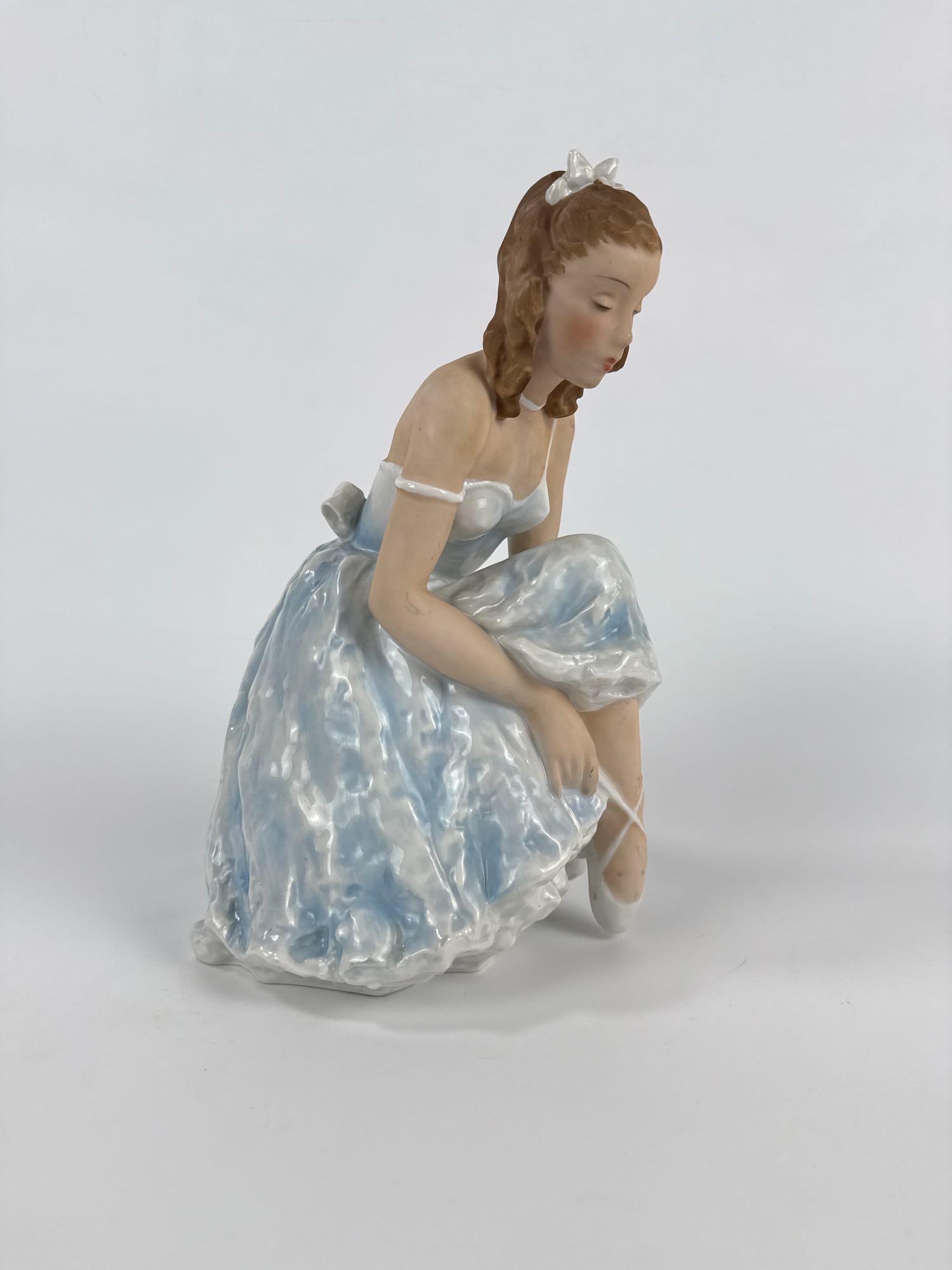 VINTAGE ROSENTHAL GERMANY "SHOE BINDER" BALLERINA PORCELAIN FIGURINE: Fine porcelain sculpture of a seated ballerina tying her pointe shoe, designed by Lore Friedrich-Gronau in 1947, featuring model number 1770 Approximate Dimensions: 11”h x 7”w x 6.25&rdquo