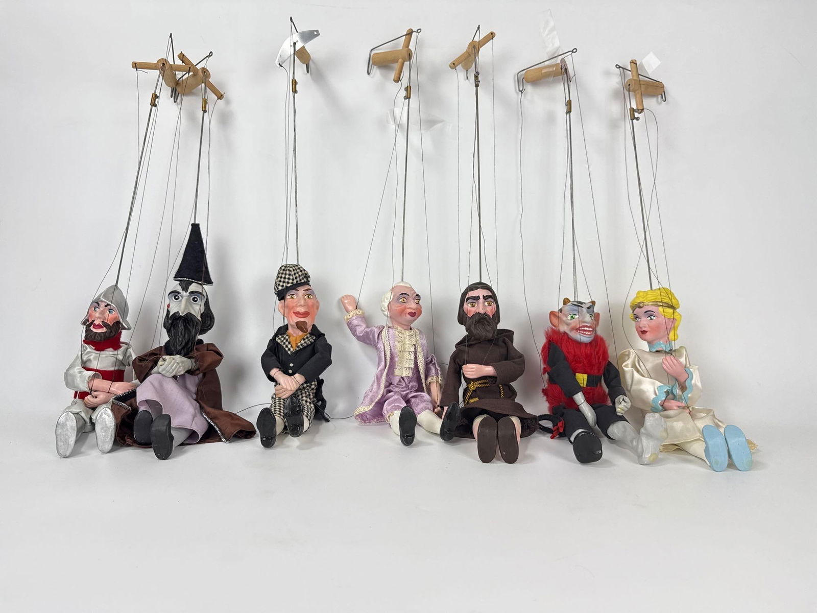 LOT OF 7 VINTAGE MID-CENTURY MARIONETTE PUPPETS PELHAM STYLE CHARACTER SET: Seven hand-painted string-operated marionettes in original theatrical costumes with wooden airplane controllers Approximate Dimensions: 22”; puppet 11” Artist or Maker: Unknown Provenance: