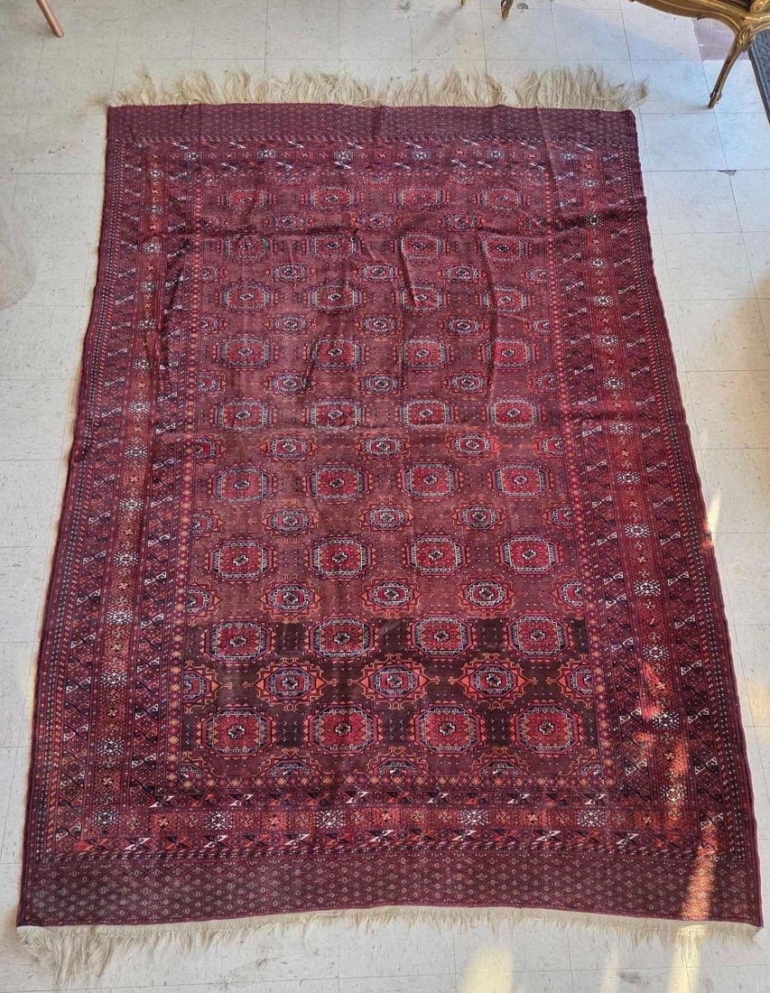 BOKHARA RUG IN REDS AND BROWNS: A classic hand-knotted wool Bokhara rug featuring a dense field of traditional "elephant foot" octagonal guls in a rich palette of deep reds, mahoganies, and chocolate browns. The rug is finis