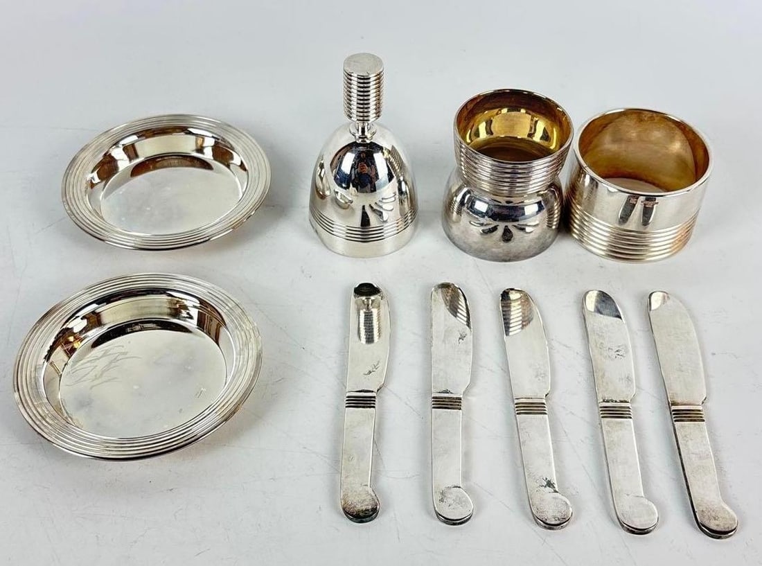 LUC LANEL FOR CHRISTOFLE ART DECO SILVER-PLATED TABLEWARE COLLECTION: A collection of high-quality European silver-plate entertaining essentials including butter knives, a bell, egg holder, napkin ring, and two wine bottle coasters. Approximate Dimensions: 3"Dia Ap