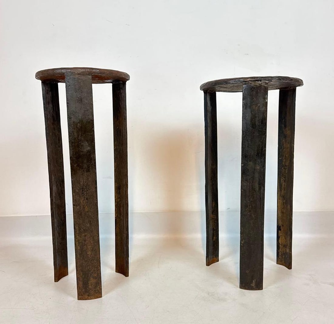 PAIR OF ROBERT FERRARONI BRUTALIST FORGED STEEL PEDESTAL TABLES: Pair of circular hand-forged patinated steel pedestal tables featuring thick round tops supported by three heavy vertical slab legs with organic textured edges. Approximate Dimensions: 21.5”h x