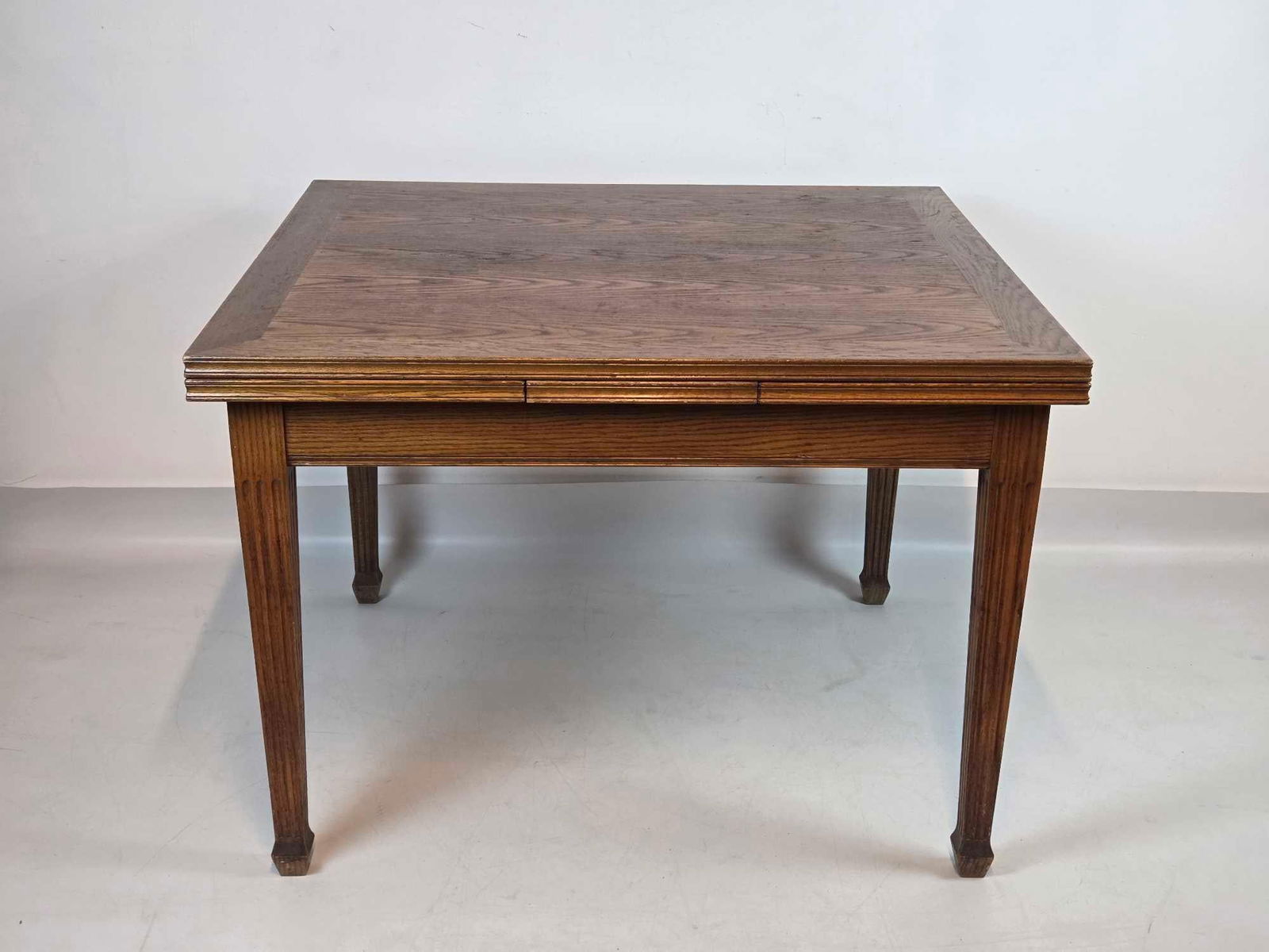 DON RUSEAU CUSTOM OAK WOOD DRAW-LEAF DINING REFRACTORY TABLE (1 OF 2): Rectangular solid oak dining surface with two lateral pull-out extension leaves on fluted tapered legs. Approximate Dimensions:29.5"h x 42"w x 38"d closed. 29.5"h x 70"w x