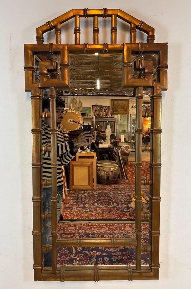 VINTAGE HOLLYWOOD REGENCY FAUX BAMBOO MIRROR: A gold-toned wall mirror with a faux bamboo frame. Approximate Dimensions: 46"L x 24"W Maker: Unknown Provenance: From a New York Collector Notes: Although care is taken to