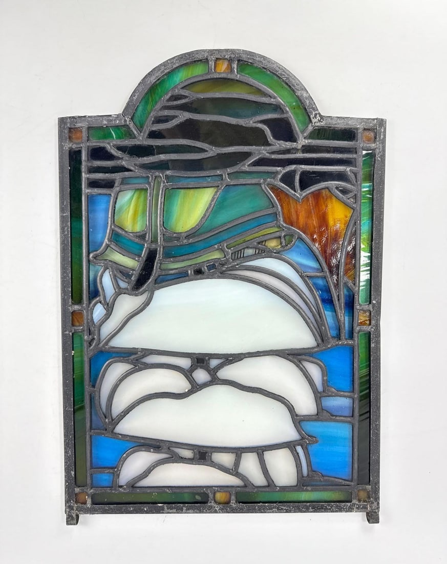 STAINED AND SLAG GLASS PANEL: An arched glass window panel made of multi-colored slag and opalescent glass in an abstract motif. Approximate Dimensions: 21.5”H x 15”W Artist or Maker: Unknown Provenance: From a New