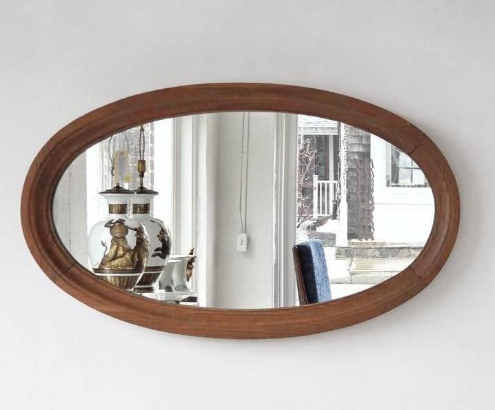 VINTAGE OVAL WOOD FRAMED WALL MIRROR: Classic oval-shaped wall mirror set within a simple tapered wood frame. Approximate Dimensions: 32.5" X 18.5" Artist or Maker: Unknown Provenance: From a New York Collector Notes: A