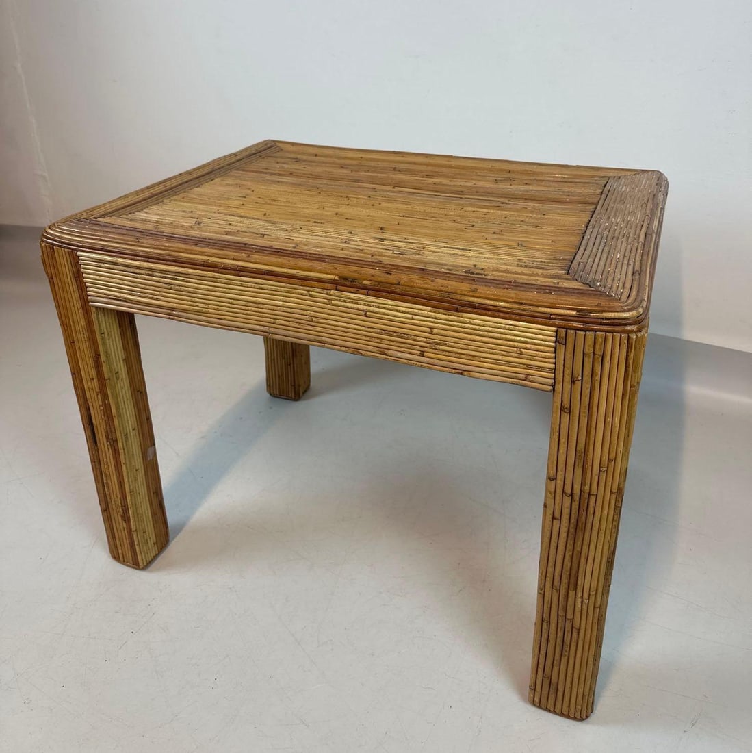 VINTAGE MID-CENTURY PENCIL REED RATTAN SIDE TABLE: *Boho-chic 1970s accent table with organic pencil reed construction and a geometric woven pattern. Approximate Dimensions: 29” x 22” x 22”h Artist or Maker: Unknown