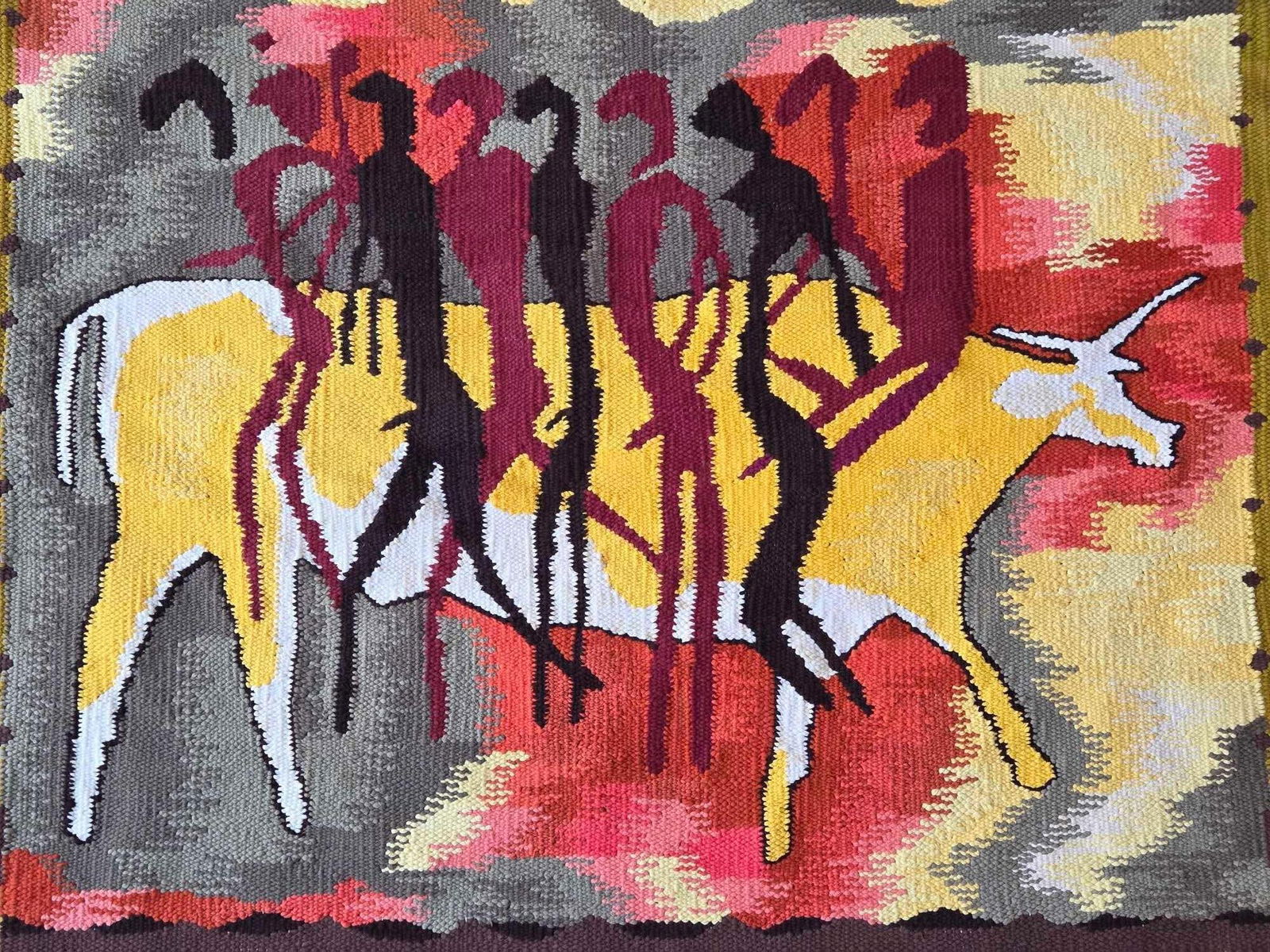 MID CENTURY MODERN ABSTRACT TEXTILE WALL HANGING: *Mid-century modern hand-woven wool tapestry depicting stylized human figures and a horned animal against a vibrant geometric background. Approximate Dimensions: 40" x 33" Artist or Maker: Unk