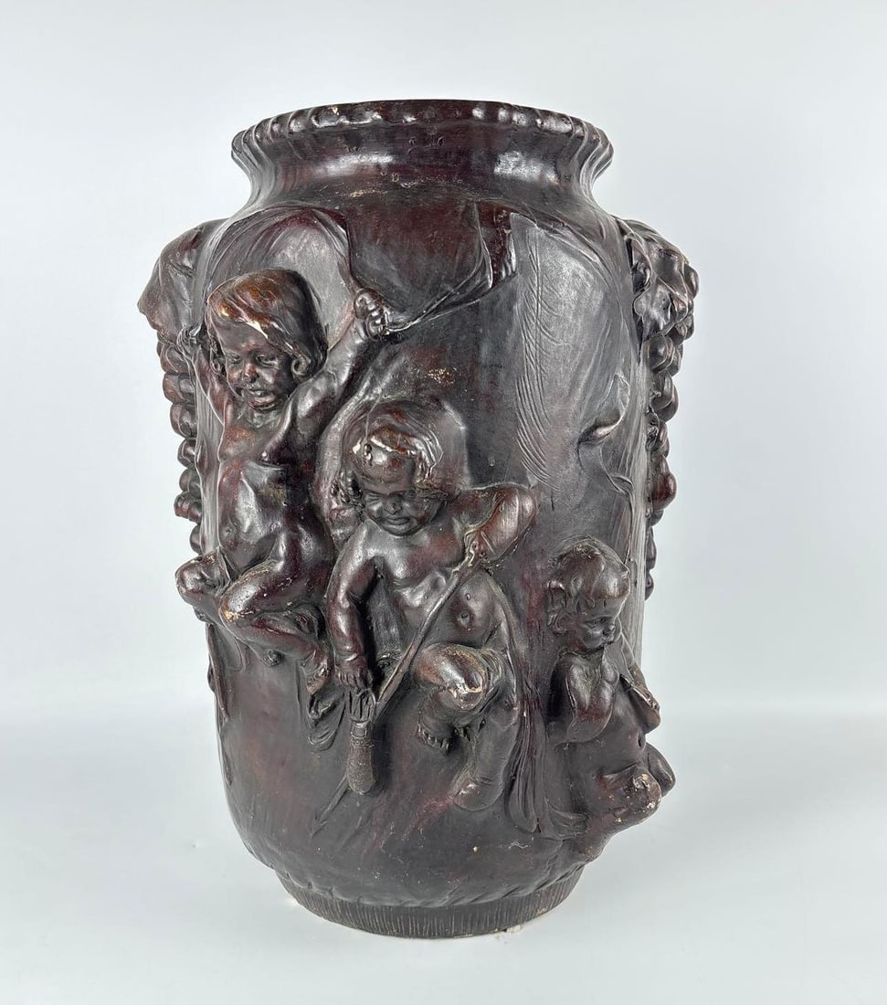 ANTIQUE GLAZED POTTERY FIGURAL BACCHIC VESSEL WITH PUTTI AND GRAPE CLUSTERS: *Chocolate-brown bronzed finish ceramic urn adorned with high-relief neoclassical cherubs playing among heavy fruiting grapevine boughs and foliate borders. Marked and numbered on bottom indecipherabl