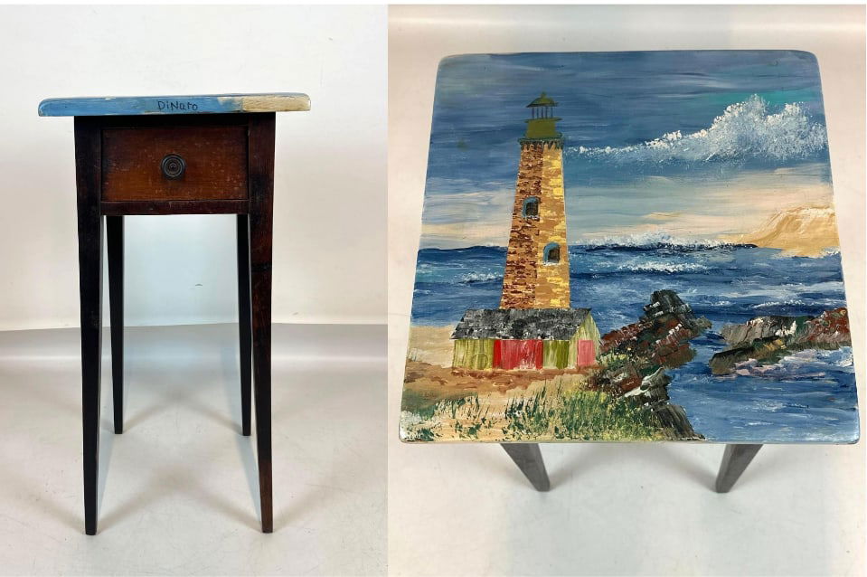 VINTAGE FOLK ART HAND PAINTED LIGHTHOUSE SIDE TABLE BYJOHN DINARO: *A hand-painted wooden side table with a single drawer featuring a coastal lighthouse landscape scene on the tabletop, signed. Approximate Dimensions: 30"H x 14"W x 14"D Artist: John DiN
