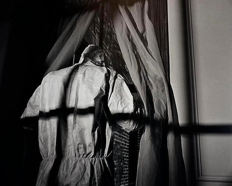 MOUNTED CONTEMPORARY BLACK AND WHITE PHOTOGRAPH OF FIGURE IN HAZMAT SUIT: *Large-format monochromatic fine art photograph mounted on board depicting a rear-view silhouette of a figure in a protective suit looking through a window with high-contrast dramatic lighting Dimens