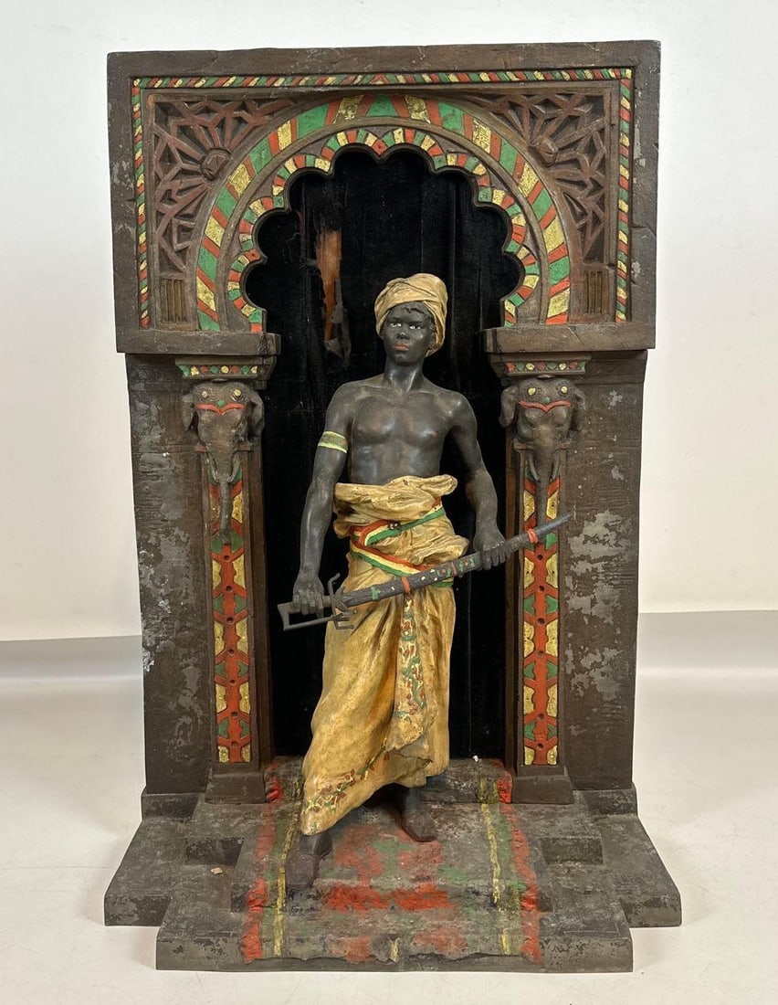 ANTIQUE FRENCH ORIENTALIST COLD-PAINTED SPELTER SCULPTURE OF A GUARD: *Polychrome metal figure of a Nubian warrior holding a sword within an architectural Moorish archway flanked by elephant head capitals. Approximate Dimensions: 38.5"h x 24"w x 12"d Artist