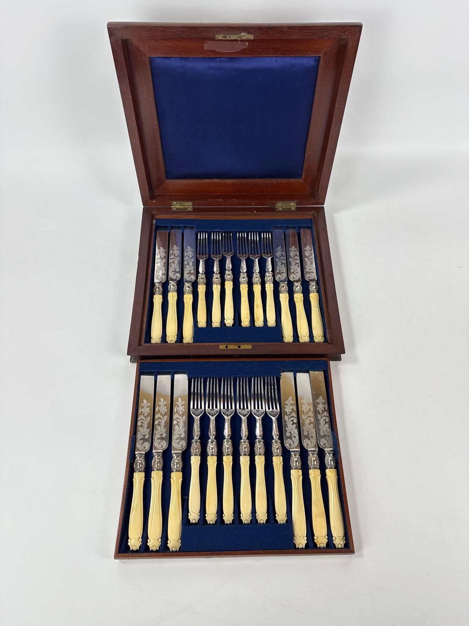 ANTIQUE CASED EARLY VICTORIAN SILVER ORNATE FORK AND KNIFE SET: *Twenty-four piece Victorian era flatware set including twelve knives and twelve forks with ornate engraved blades in a fitted mahogany presentation case. Approximate Dimensions: Case 2.25”h x