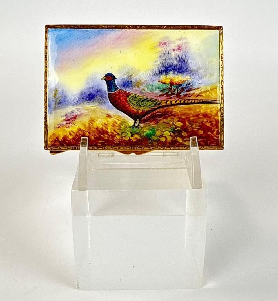 VINTAGE HAND PAINTED ENAMEL AND BRASS COMPACT WITH PHEASANT MOTIF: Rectangular brass vanity case decorated with a vivid kiln-fired enamel pastoral scene depicting a ring-necked pheasant in a colorful autumn landscape. Approximate Dimensions: 3/8”h x 3”w