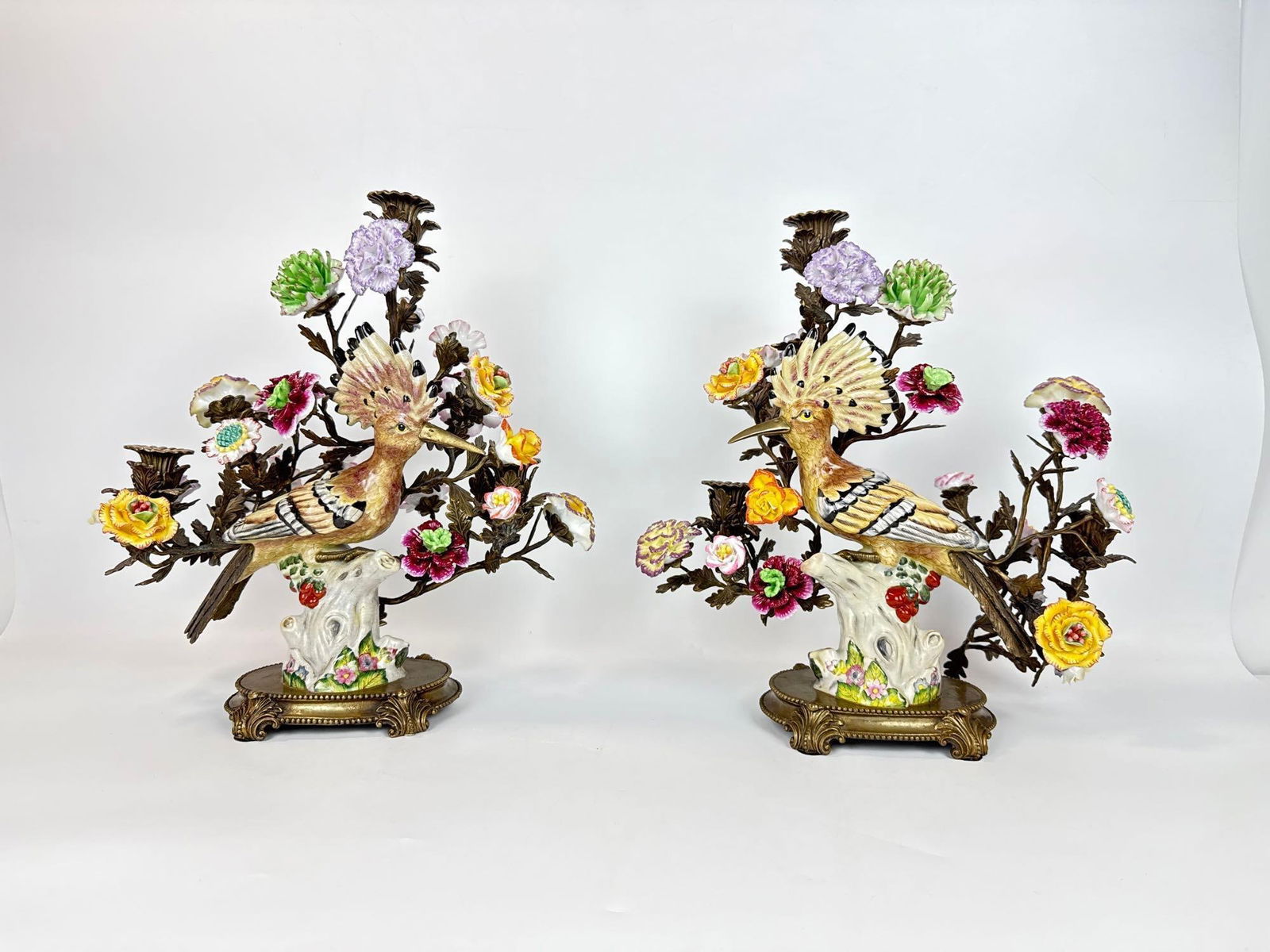 PAIR OF LARGE CASTILIAN PORCELAIN AND BRASS HOOPOE BIRD CANDELABRA: Modern decorative polychrome porcelain birds mounted on ornate brass floral bocage bases. Approximate Dimensions: 15.5”h x 16”w x 8”d Artist or Maker: Unknown Proven