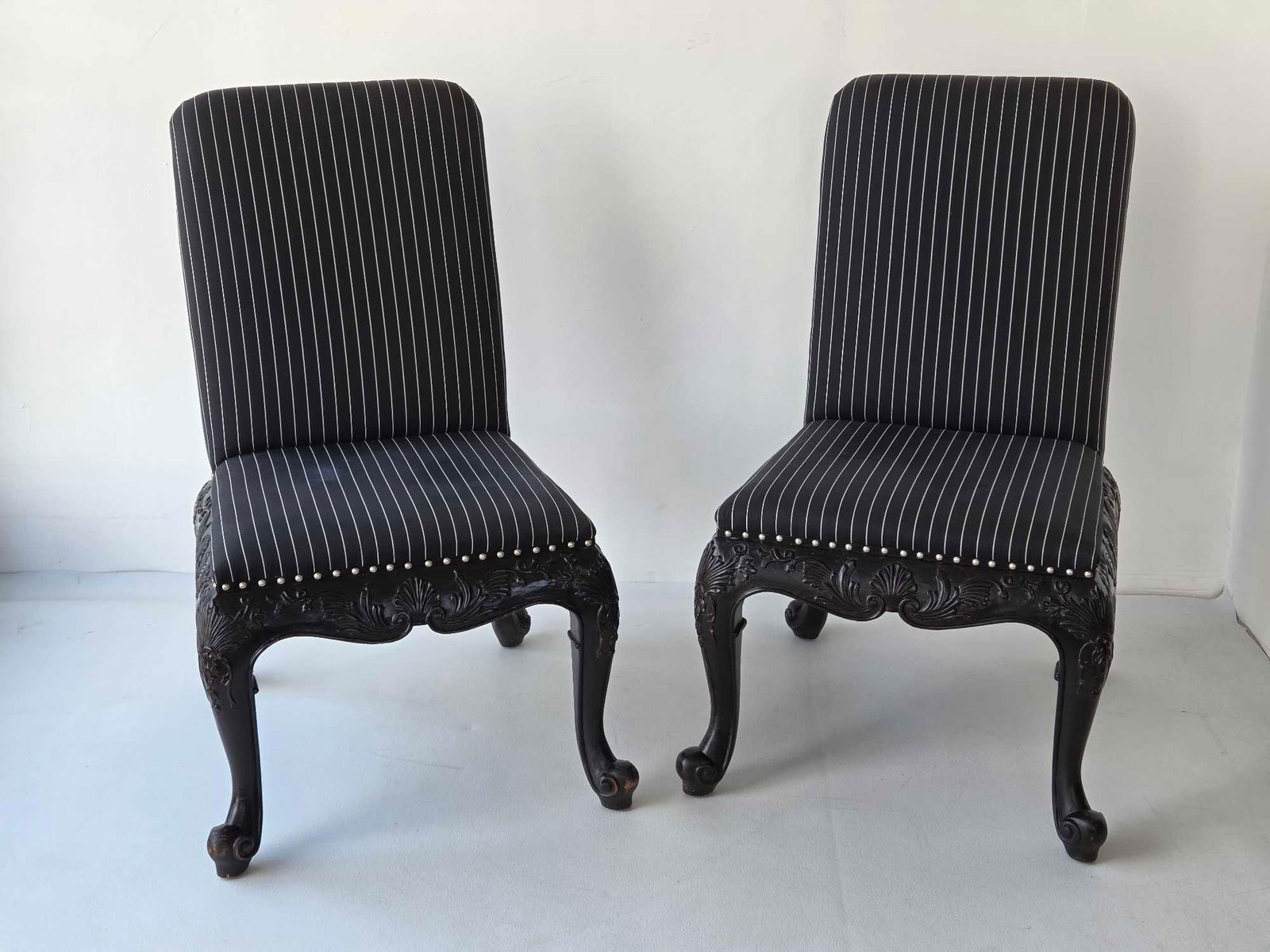 PAIR OF RALPH LAUREN HOME BEL AIR ROCOCO CARVED BLACK LACQUER SIDE CHAIRS (1 of 3): Pair of ebonized mahogany dining chairs with elaborate shell and acanthus leaf-carved aprons on cabriole legs upholstered in pinstripe fabric with silver-tone nailhead trim. Approximate Dimensions: 39