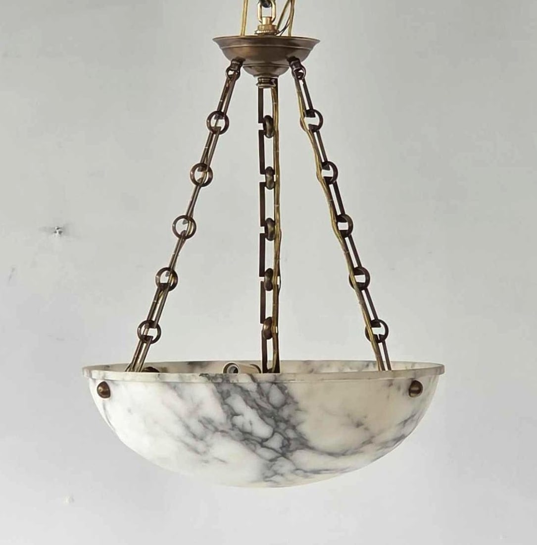 EMPIRE STYLE ALABASTER PENDANT LIGHT FIXTURE: A round, hand-carved alabaster domed dish light fixture suspended by brass chains. Approximate Dimensions: 19"H x 16"Dia / Bowl: 5"H x 16"Dia Artist or Maker: Unknown Provenance: From a New York Co