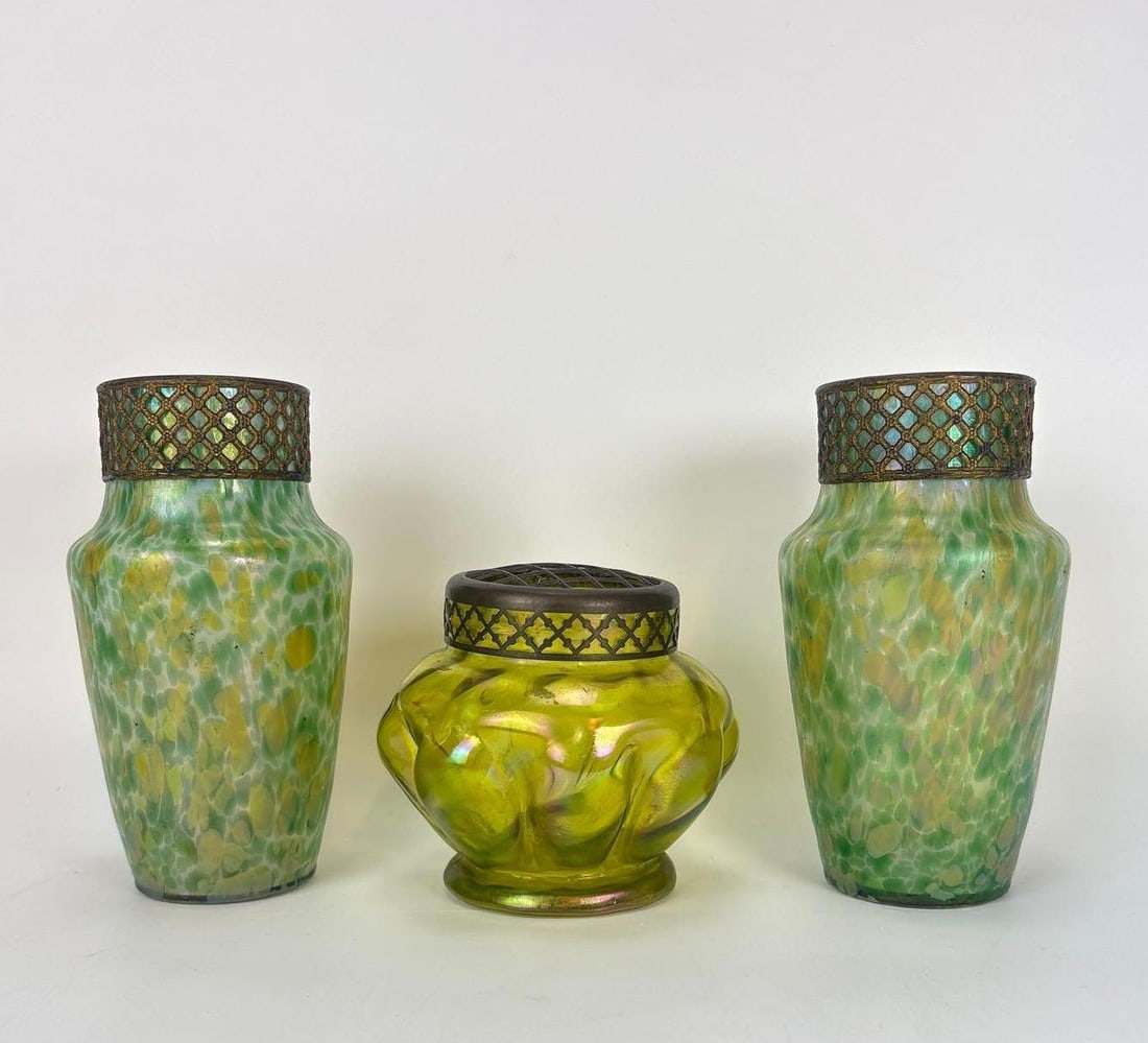 LOETZ ATTR. ART NOUVEAU BOHEMIAN GREEN GLASS VASE COLLECTION: *A lot of three Art Nouveau period green glass vessels, featuring a pair of matching mottled glass vases with ornate metal collars and a single iridescent "flower frog" vase. Approximate Dime